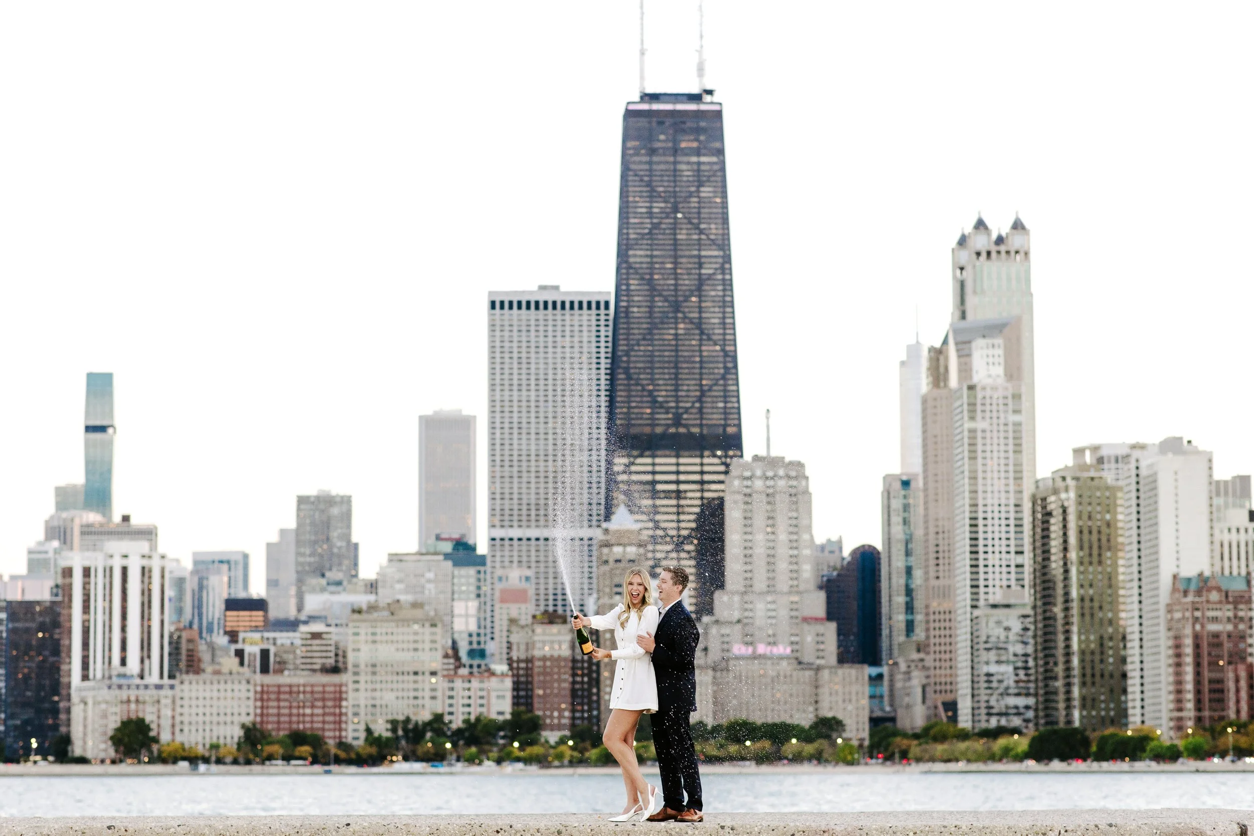 A couple celebrating with champagne on a city rooftop, with the Chicago skyline in the background.