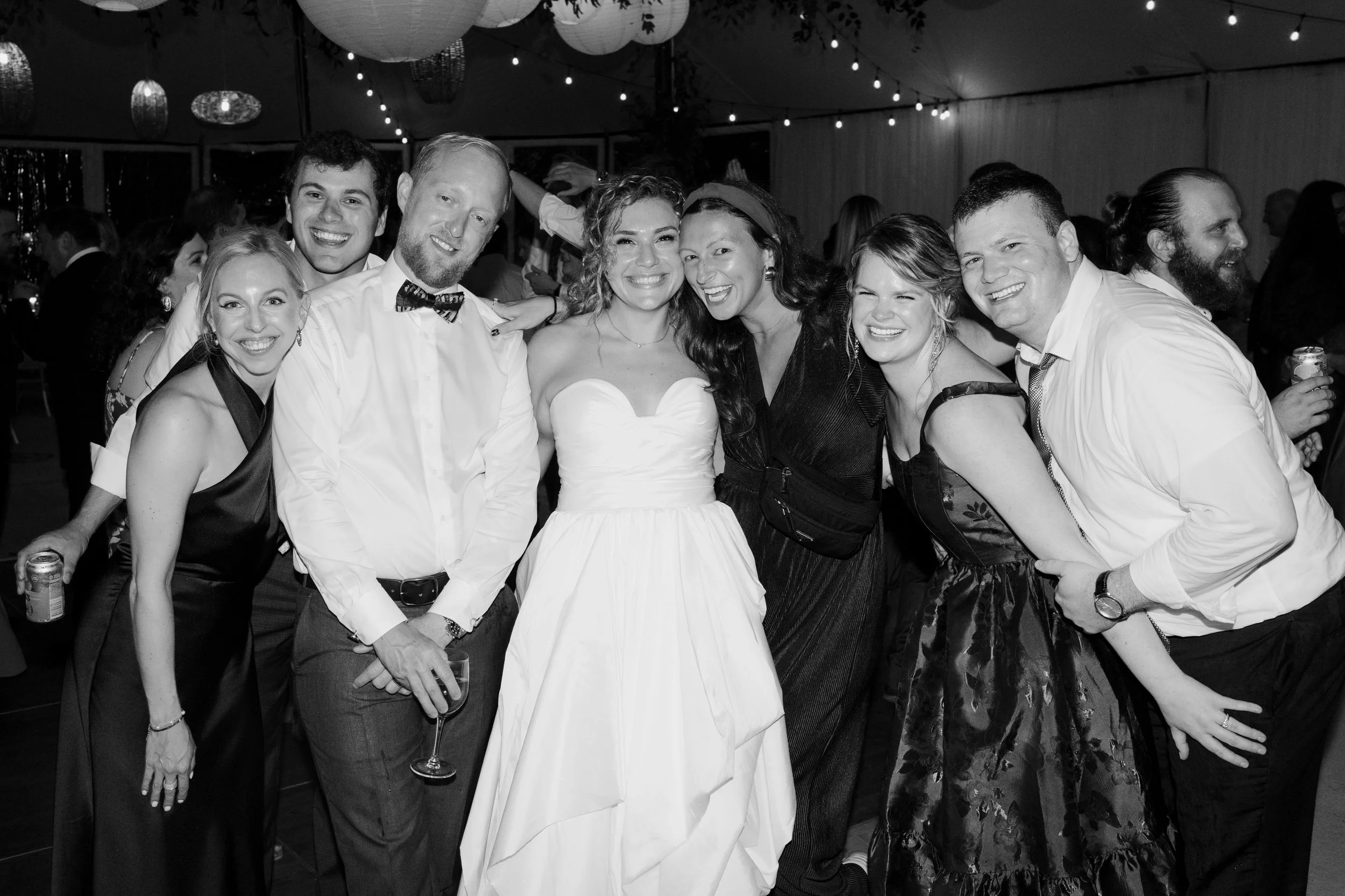 Group of people at a celebration or party, smiling and posing for a photo. The image is in black and white.