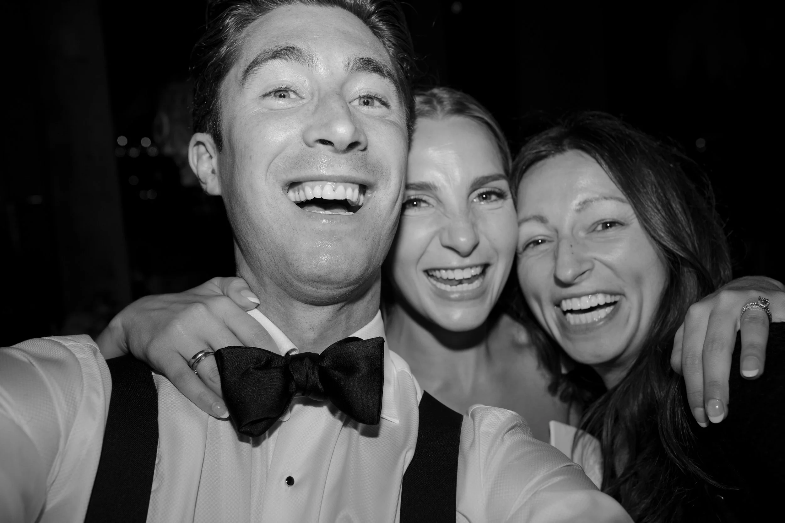 Three people taking a selfie together, smiling and looking happy, dressed in formal attire.