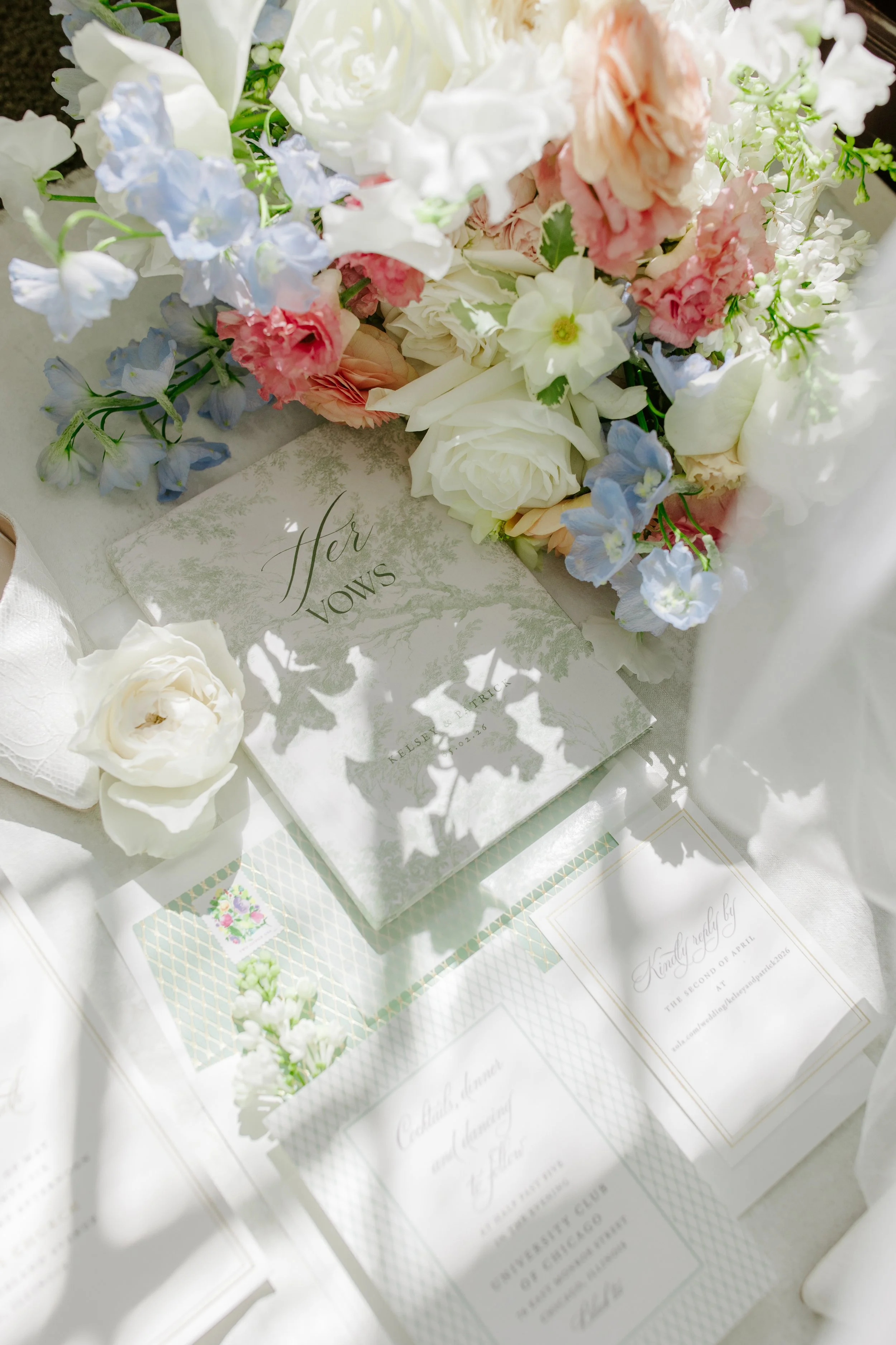 Close-up of a wedding vow card decorated with white and pink flowers on a white table.