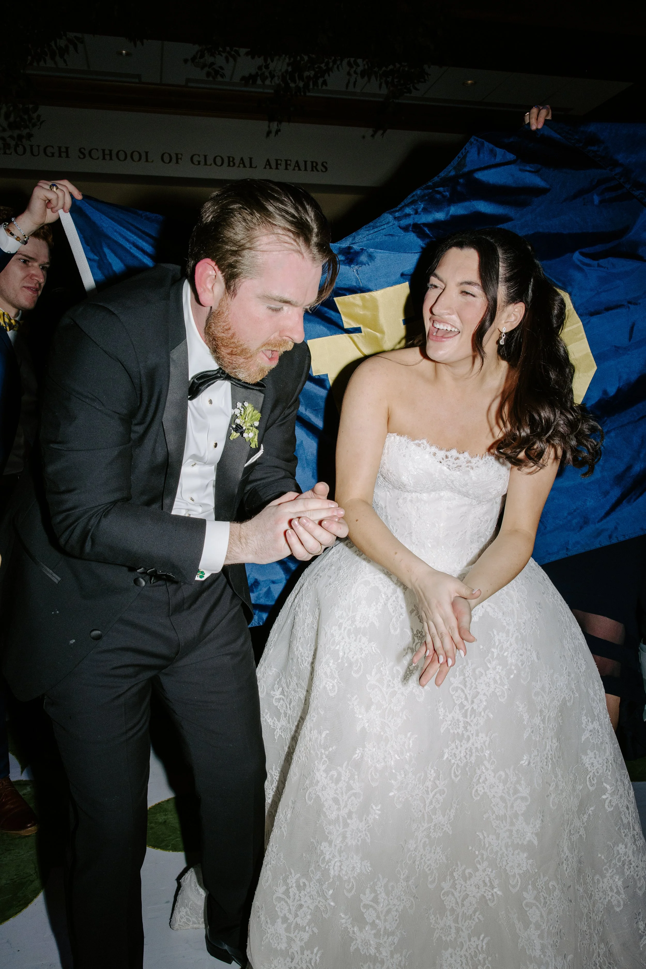Wedding couple sitting together, the groom in a tuxedo and the bride in a white wedding dress, sharing a joyful moment during their wedding celebration.