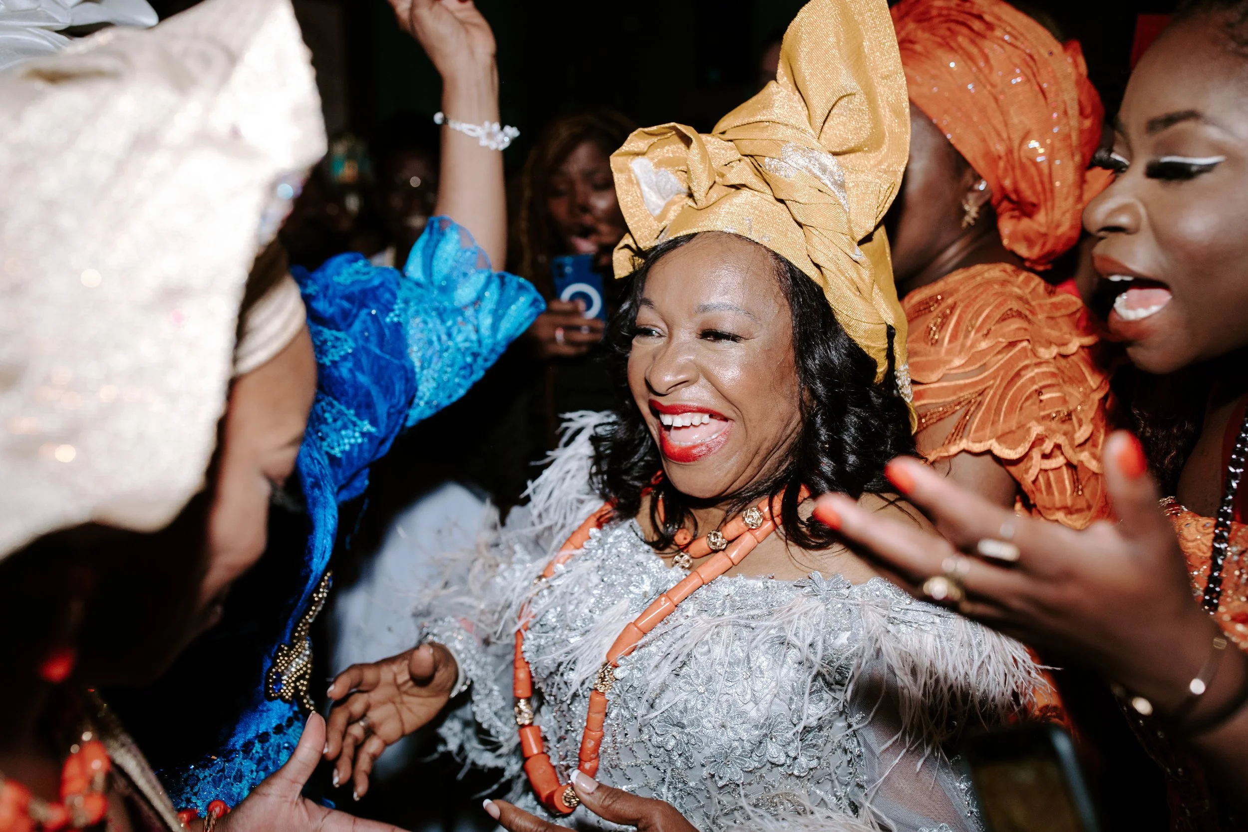 Women wearing colorful traditional African attire dancing and celebrating at a festive event.