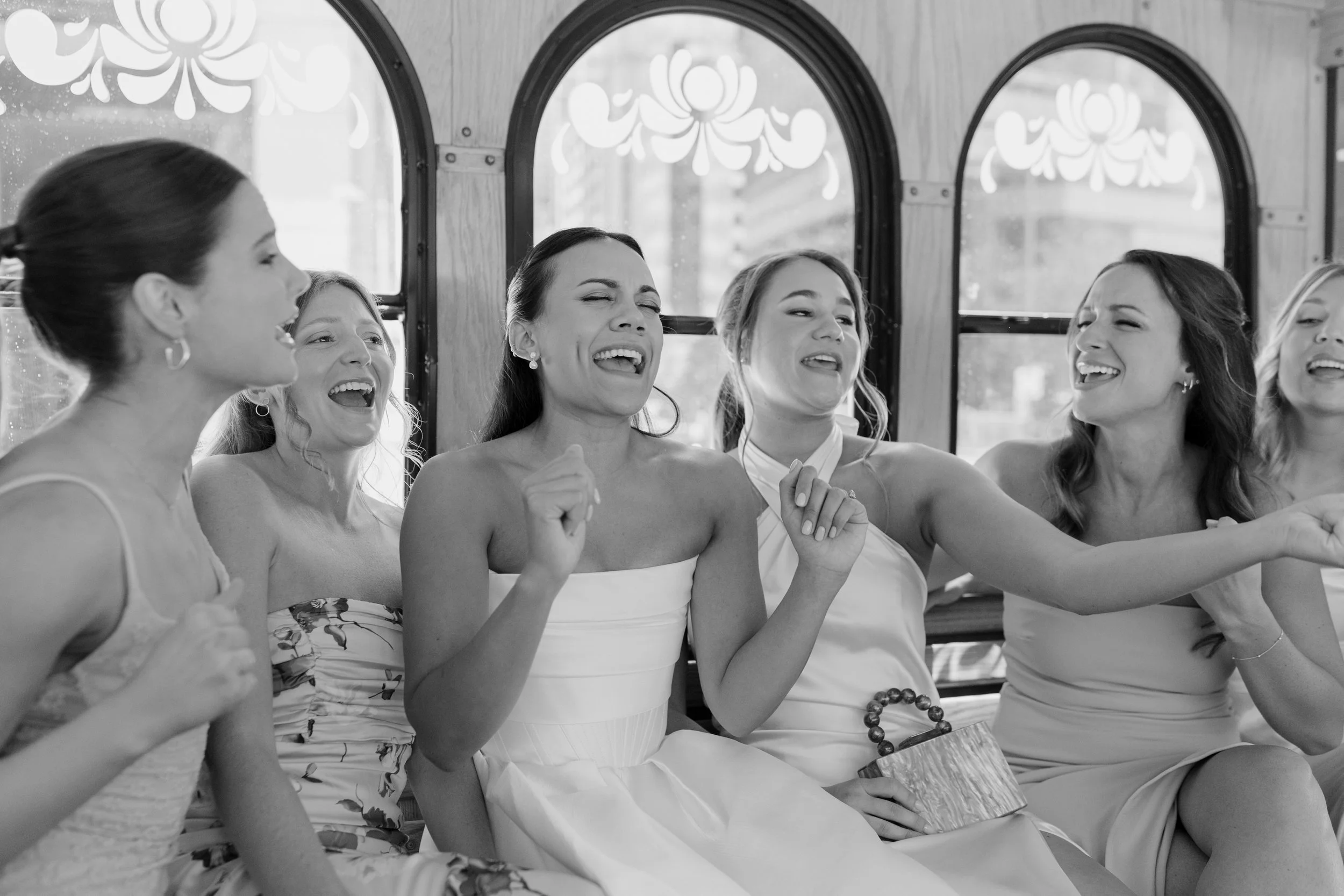 Six women sitting together, possibly at an event or gathering, enjoying a moment of laughter and conversation.