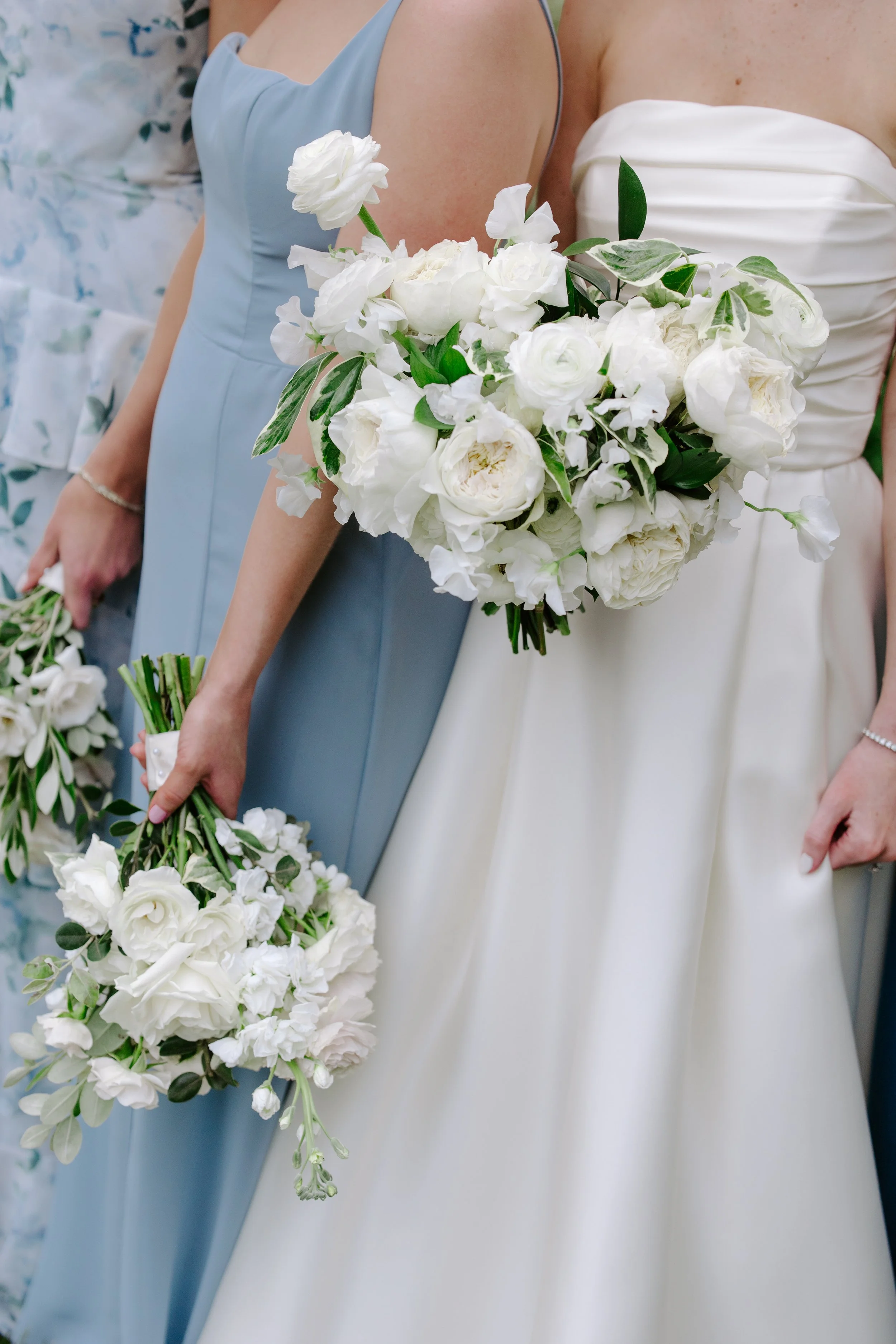 Close-up of women in wedding dresses holding white flower bouquets at a wedding.