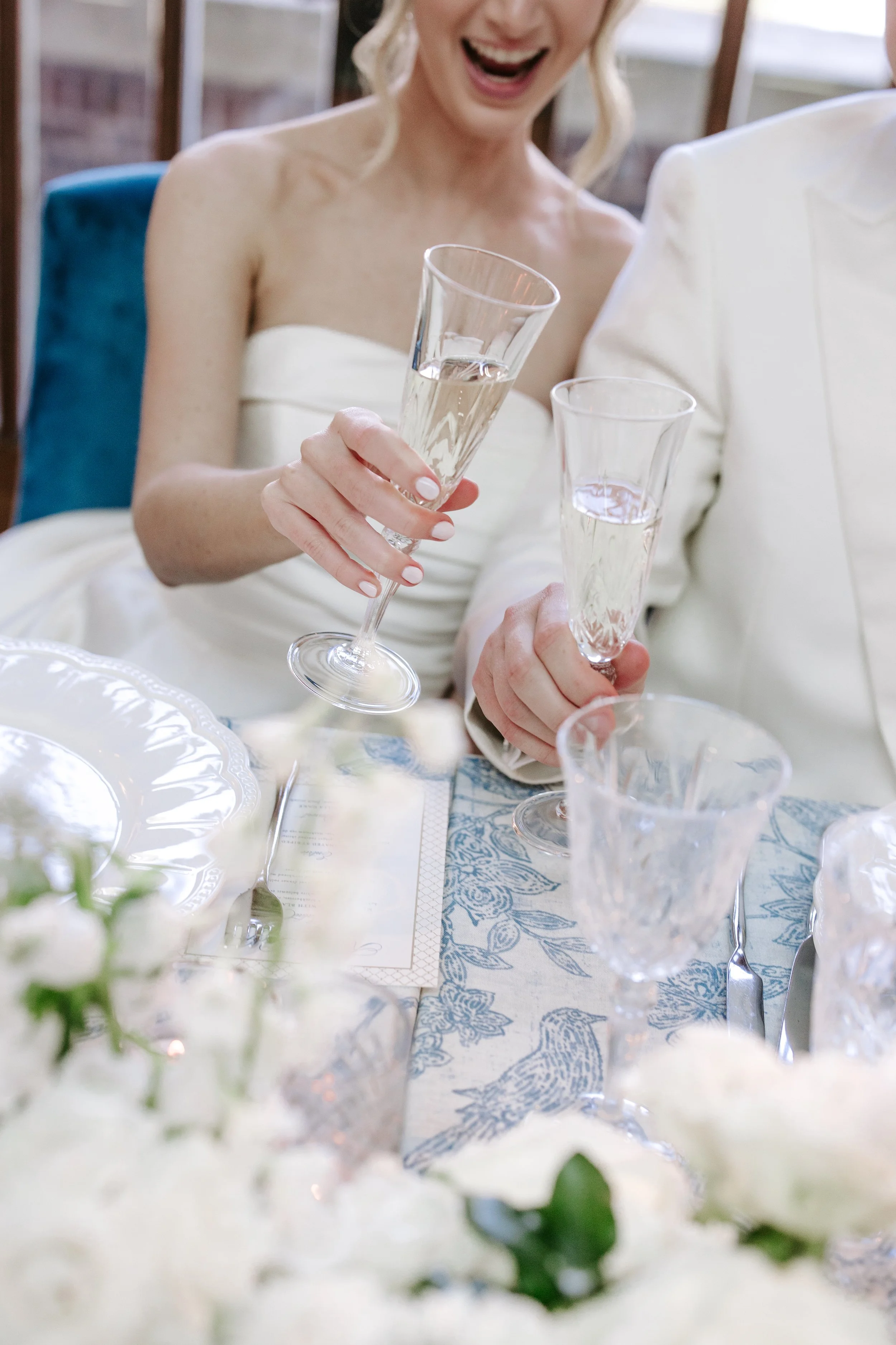 A woman in a wedding dress holding a champagne flute at a celebration dinner.
