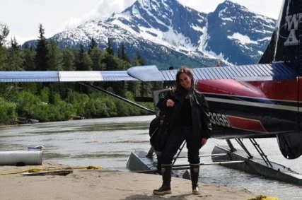 Female film director standing next to an airplane in Alaska getting ready to film with Sustainability expert and chef Barton Seaver.