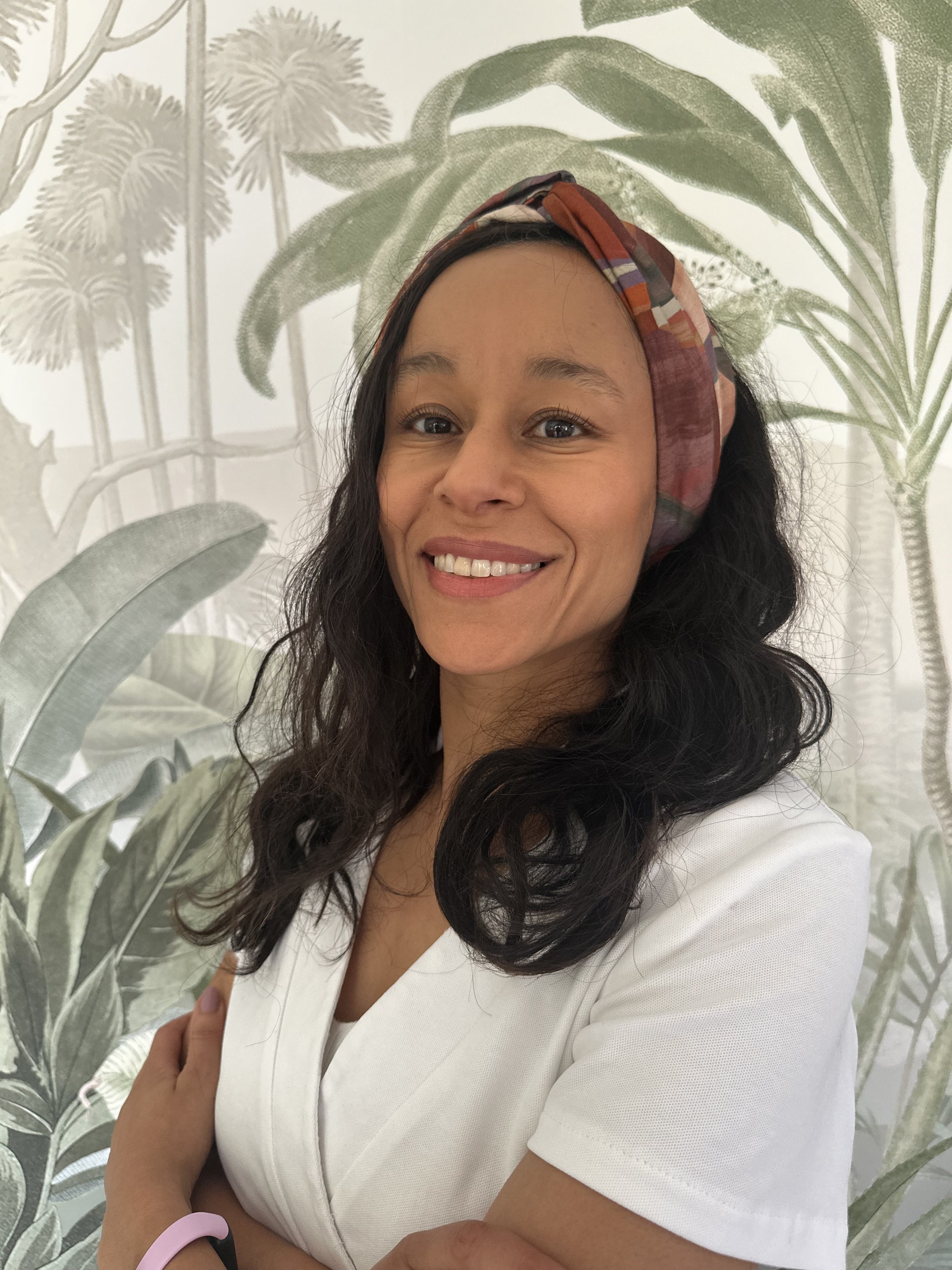 Olivia Conde, LPG Endermologie expert practitioner, the only one in Kent with the latest Cellu M6 Infinity machine, smiling while standing in front of a leafy botanical wallpaper.