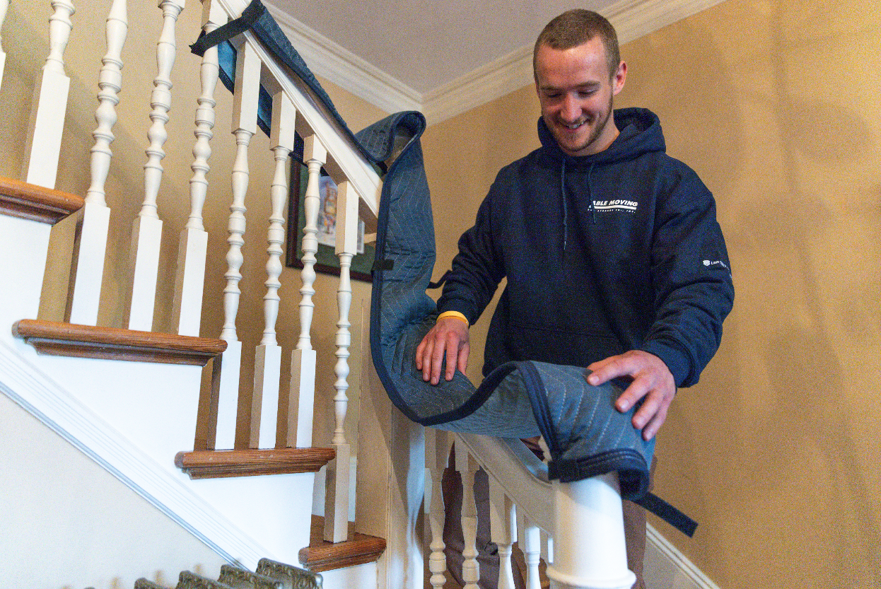 A man covering a stair railing in a protective sheet
