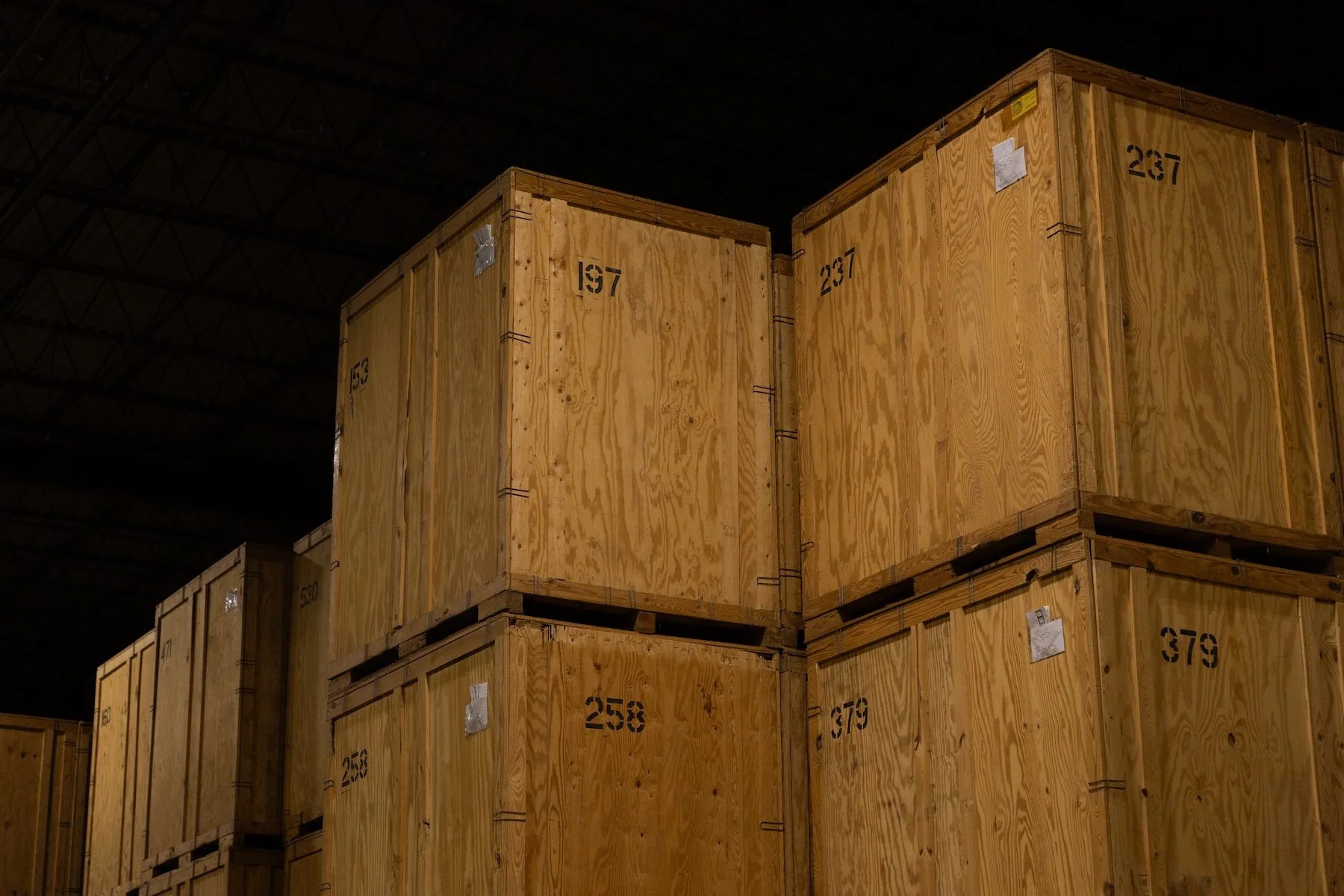 Stacked wooden crates inside a warehouse, numbered 197, 237, 258, and 879.
