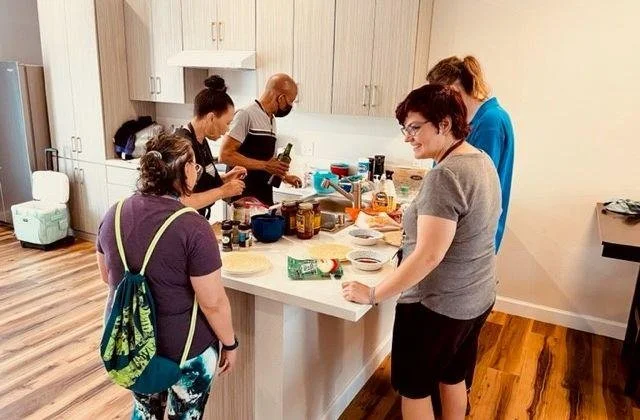 Group of five people cooking together in a modern kitchen.