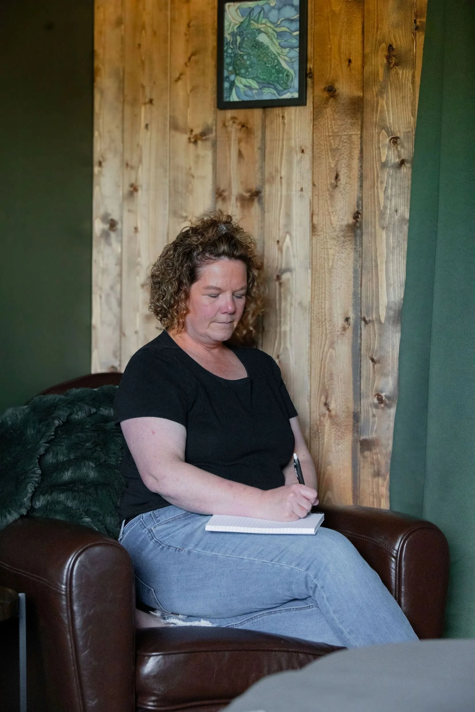 Janet Langevin taking notes during a consultation at Treestone Massage near Edmonton and Lac Ste. Anne.