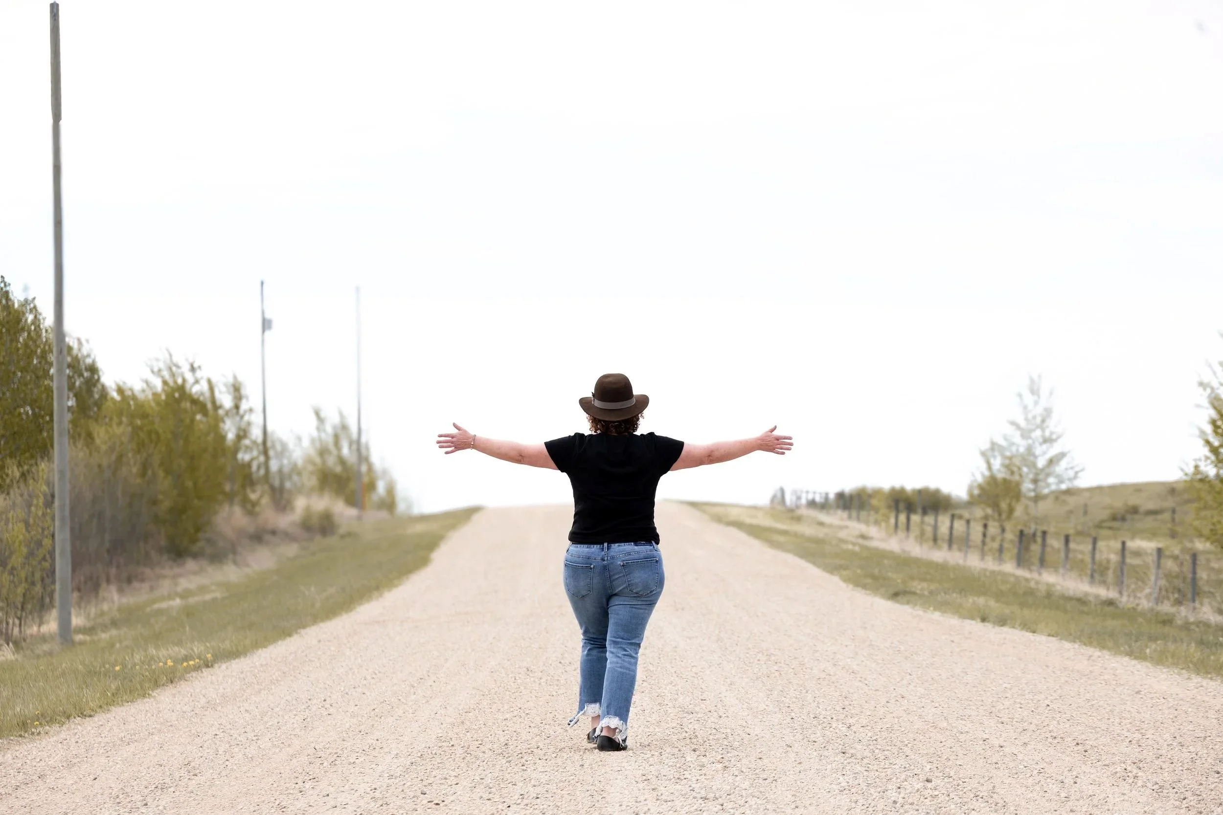 anet Langevin walking down a dirt road representing a spiritual healing journey in Alberta Canada.