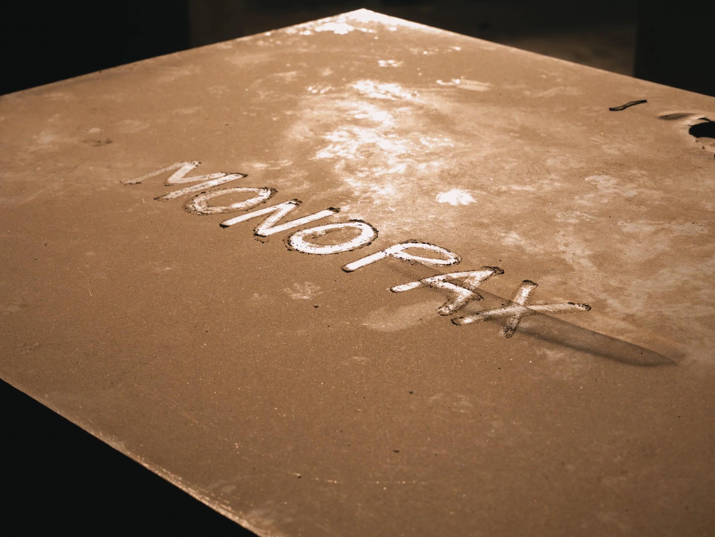 Close-up of a dusty surface with the word 'WONDER' written in white powder or chalk.