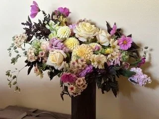 A large, tall flower arrangement in a black vase