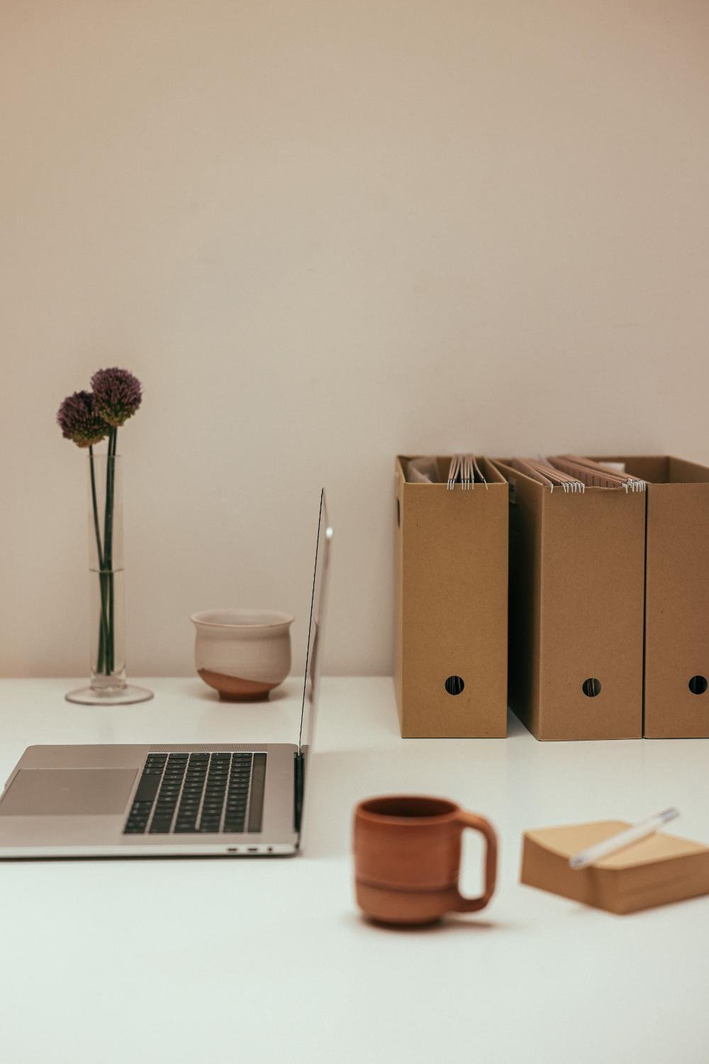 Laptop with cup and boxes with files in the background for OBM and VA packages