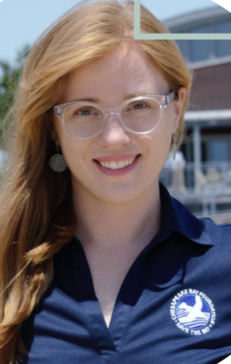 A woman with red hair and glasses smiling outdoors, wearing a navy blue shirt with a logo of a bird and text that reads 'Cheyenne Lake Bayou'.