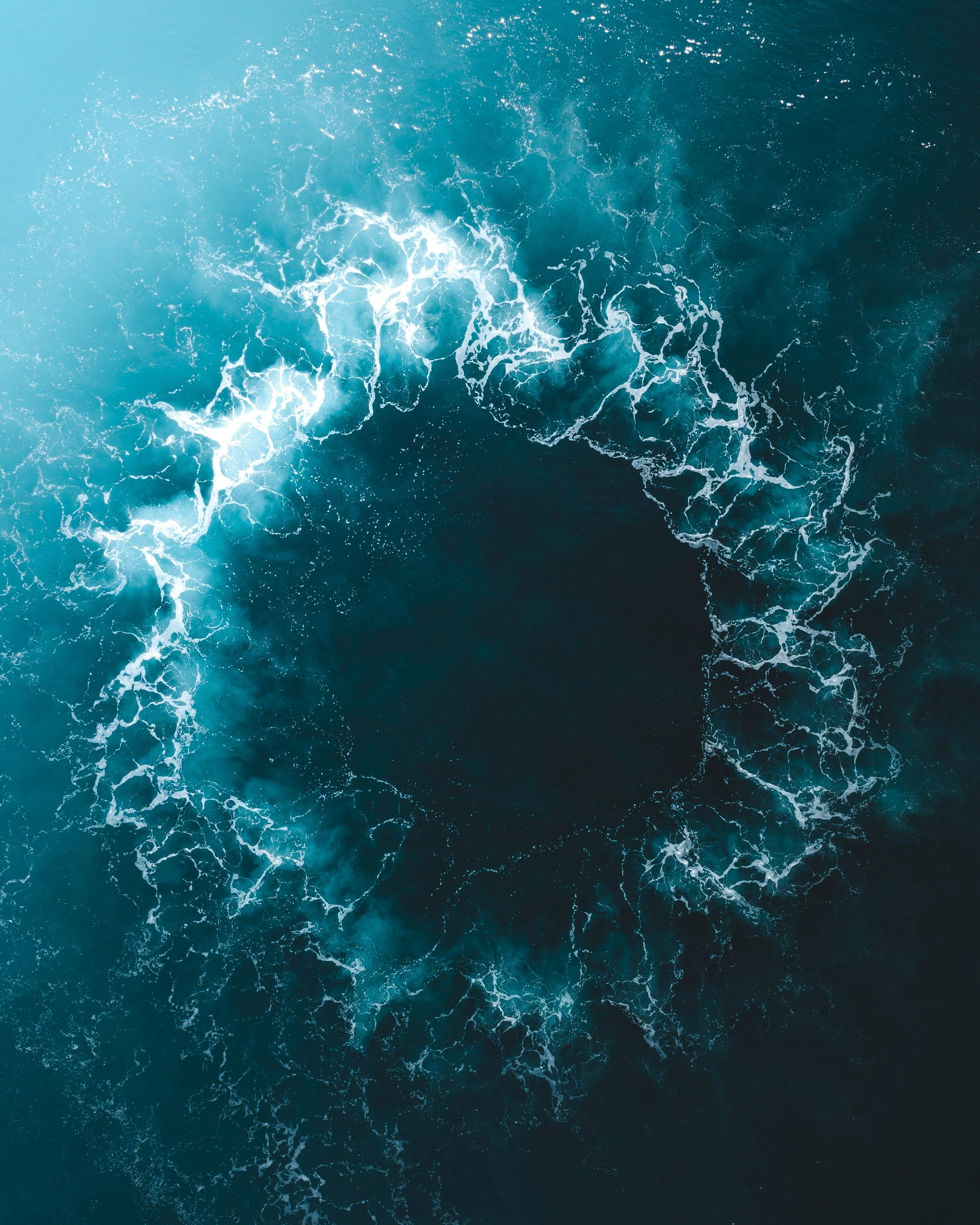Aerial view of ocean water with white foamy waves crashing on the surface