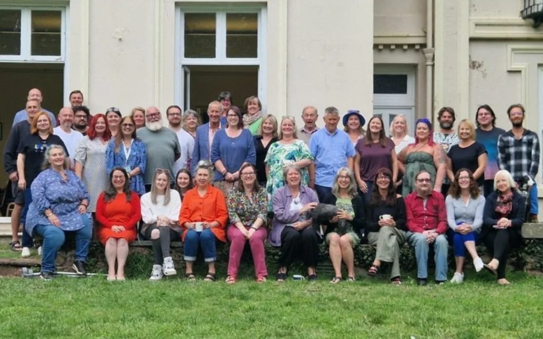 Group of people gathered outdoors in front of a building, posing for a photo.