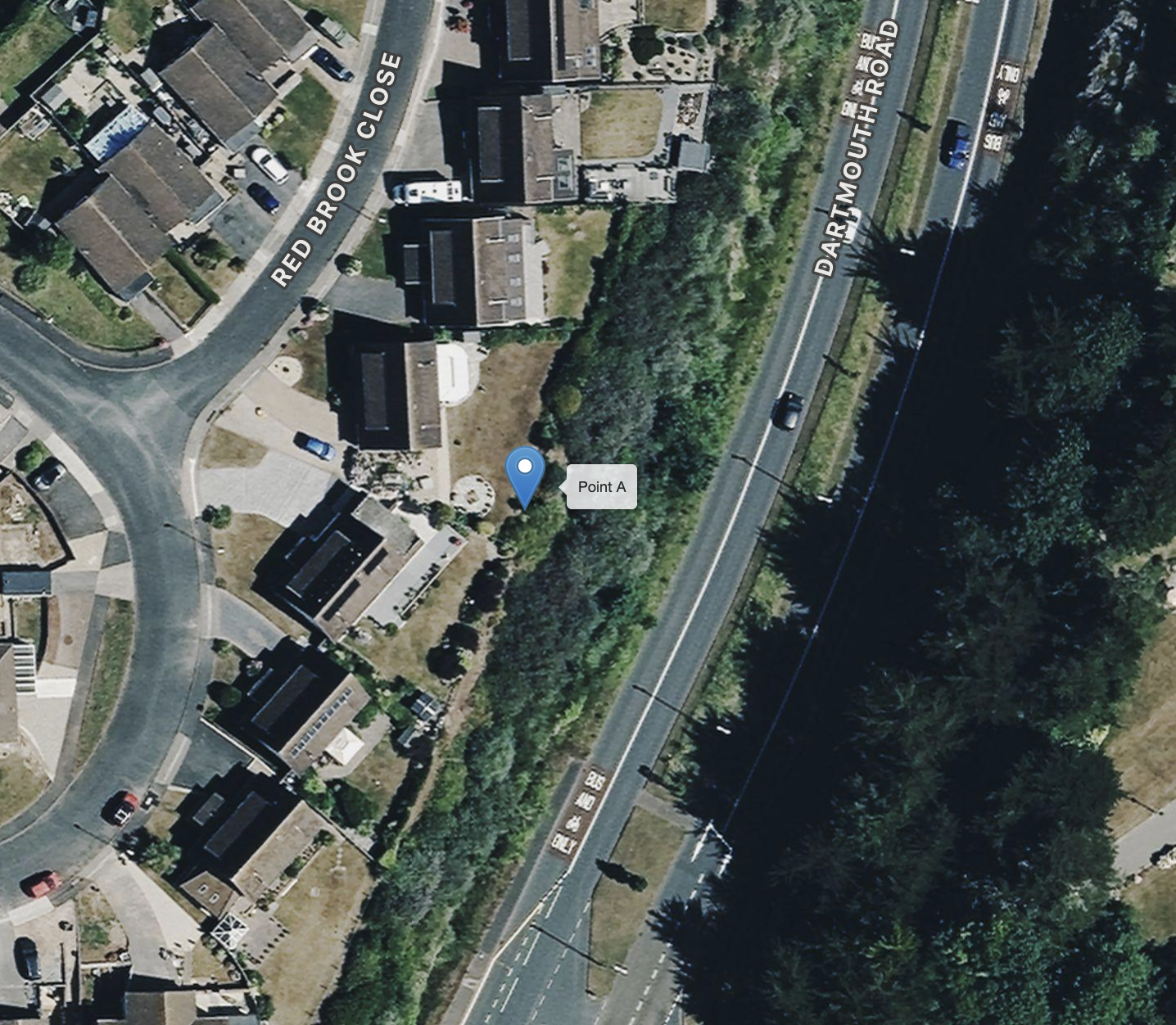 An aerial view of a residential area with several houses, roads, and a green area along a railway line. The image shows labeled streets, 'Red Brook Close' and 'Dartmouth Road,' and a marker labeled 'Point A' near a house with a backyard patio.