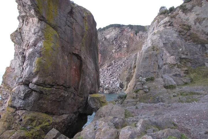 A rocky canyon with large, moss-covered boulders and a river flowing through it.