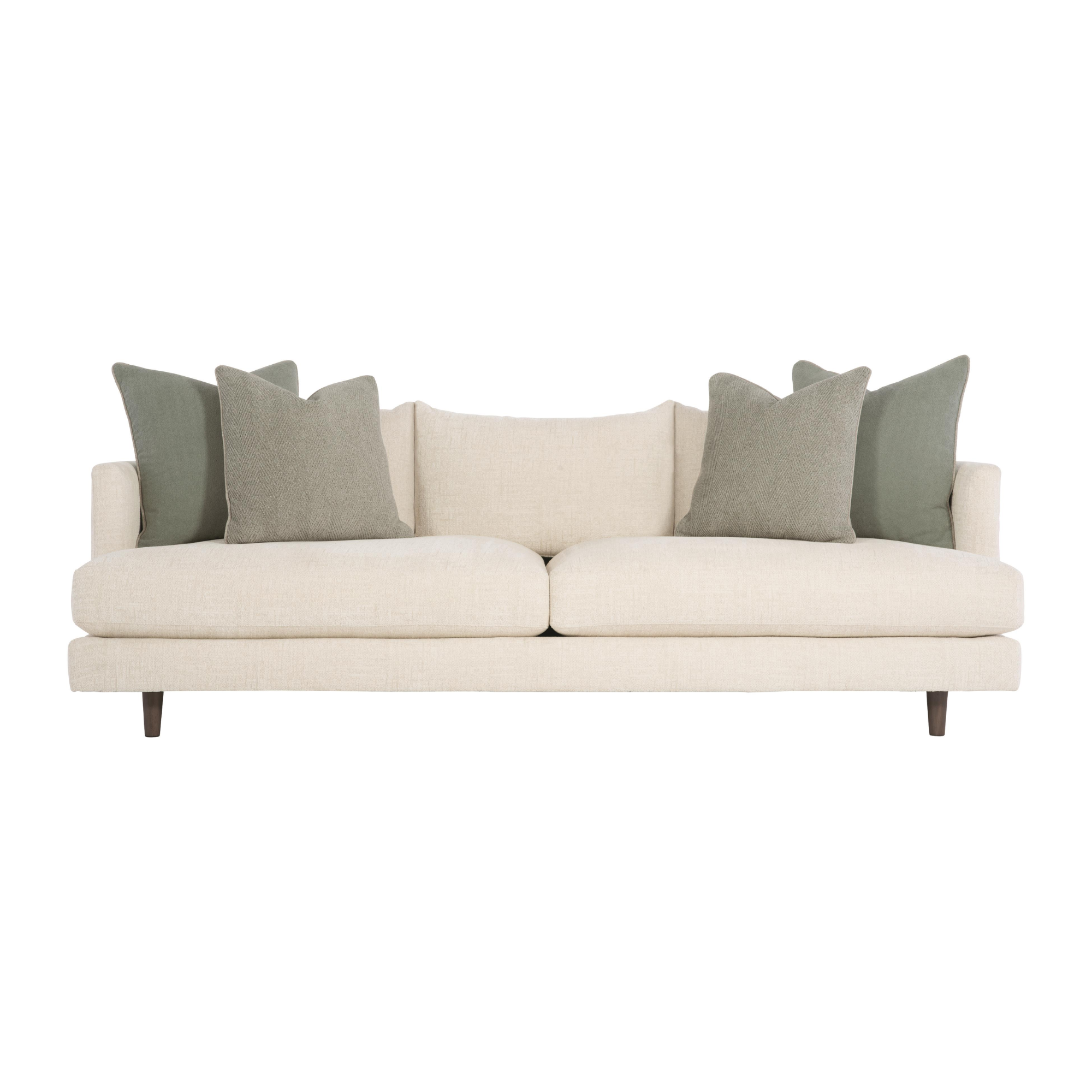 A beige sofa with five decorative pillows, three in olive green and two in light beige with custom COM fabric from bernhardt.