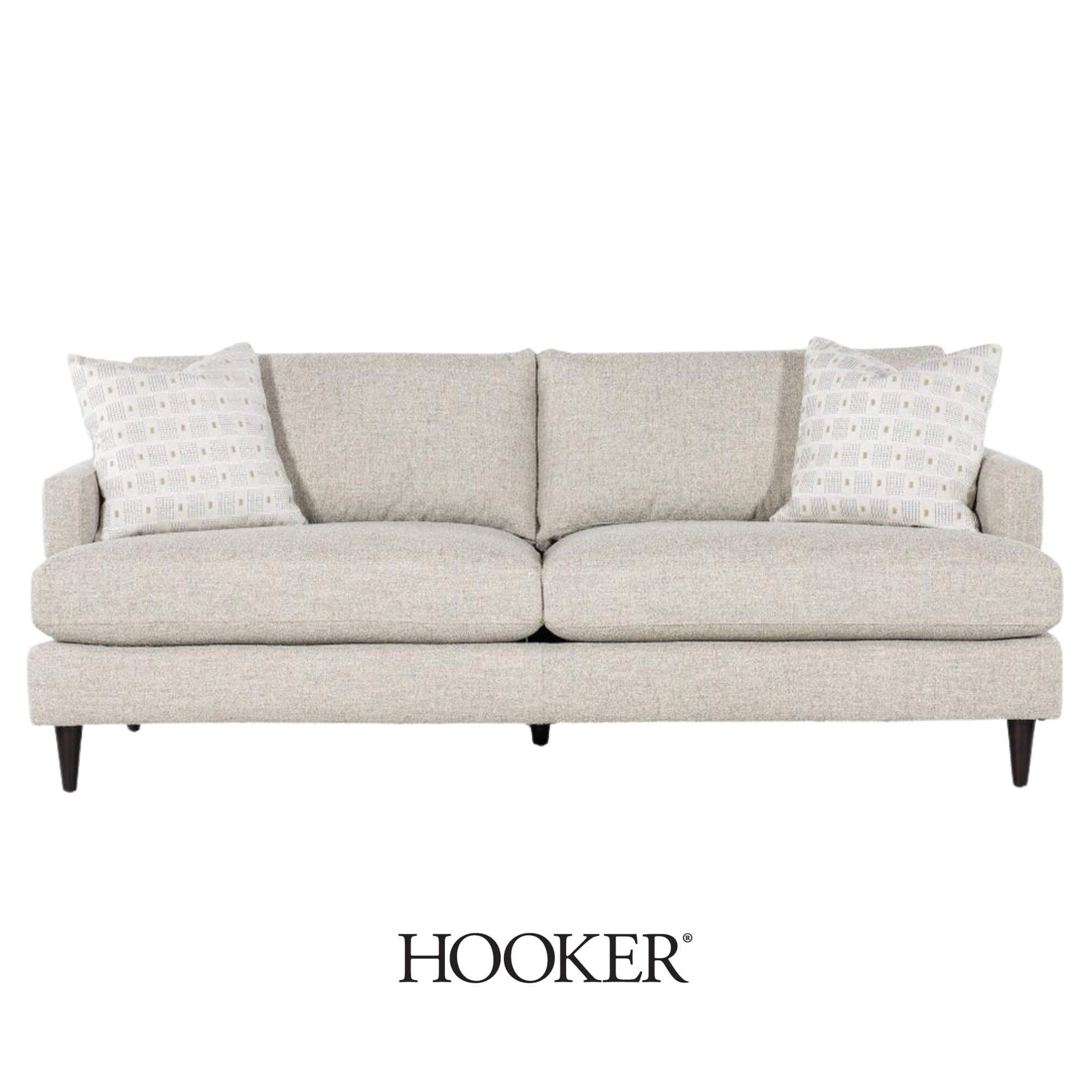 A beige sofa with two patterned throw pillows from Hooker Furniture.