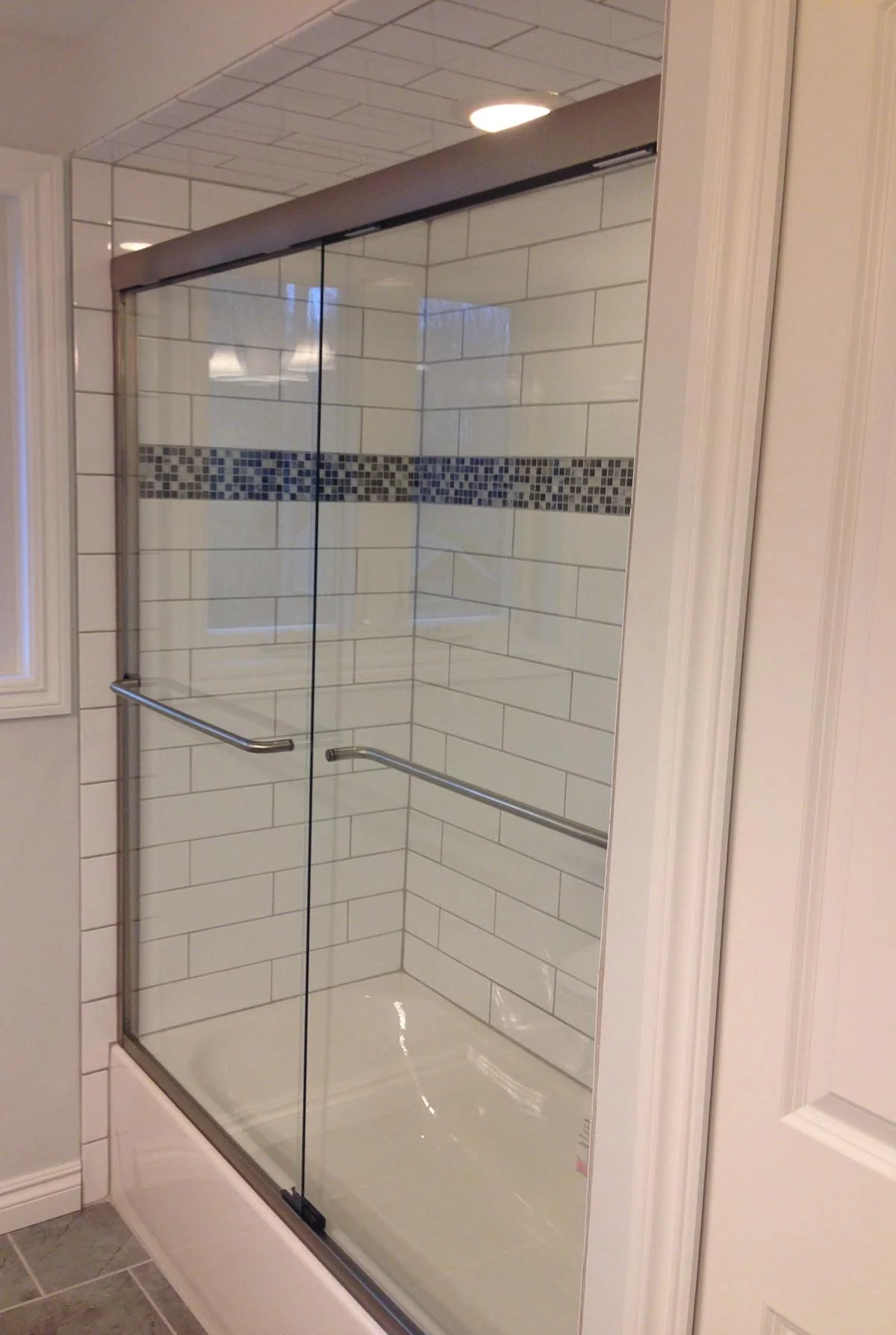 Breza hall bath included: new ceramic subway tile with black and grey accent glass, frameless tempered glass doors.