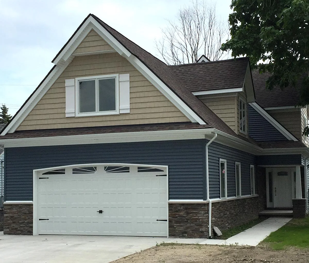 New Build. Front elevation of a custom built 2700 sq ft home (2000 sq ft finished area, 700 sq ft bonus area over the garage). Work included: new dimensional shingles, new stone knee wall, new vinyl siding and vinyl shakes, new Pella doors and window
