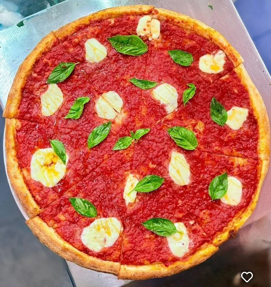 A pizza topped with tomato sauce, mozzarella cheese slices, and fresh basil leaves.