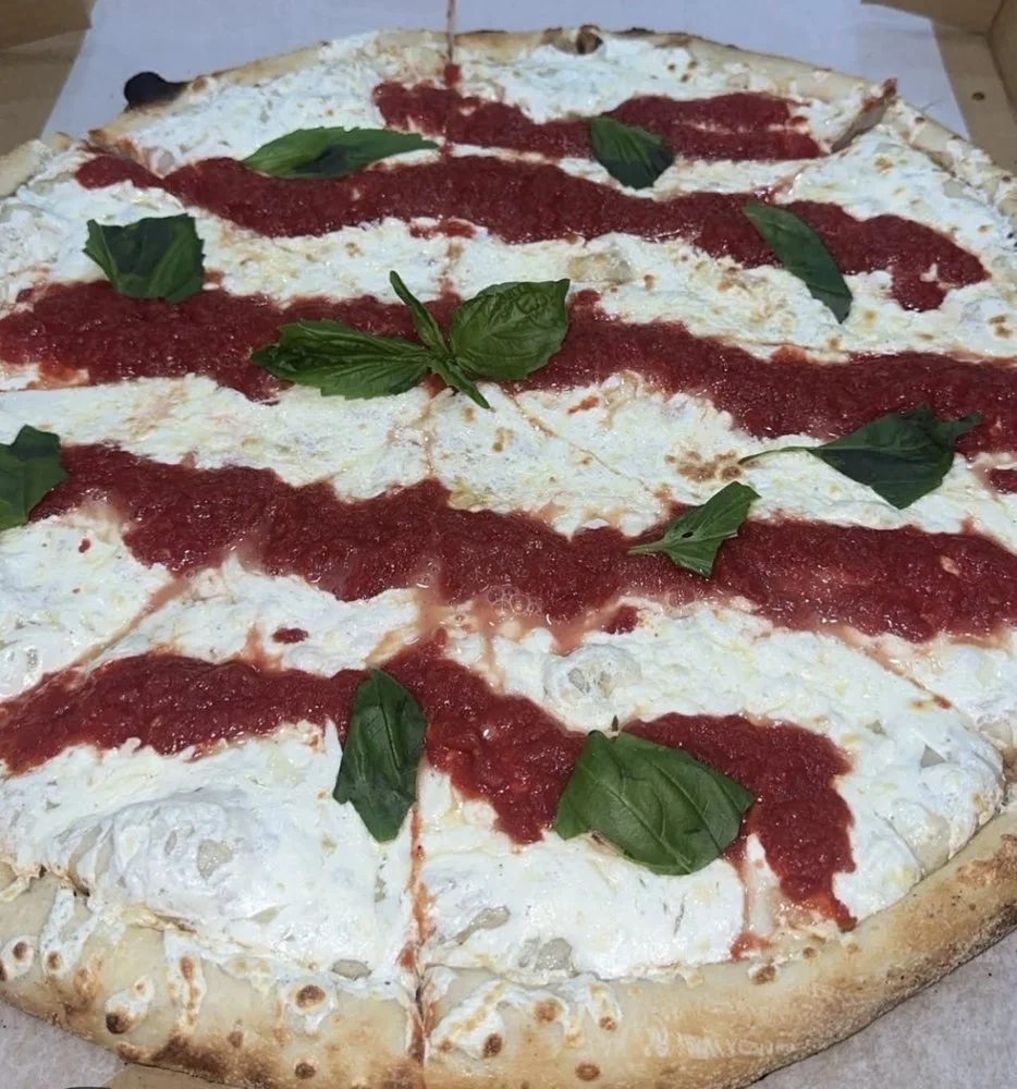 A cheese pizza with fresh basil leaves and tomato sauce stripes.