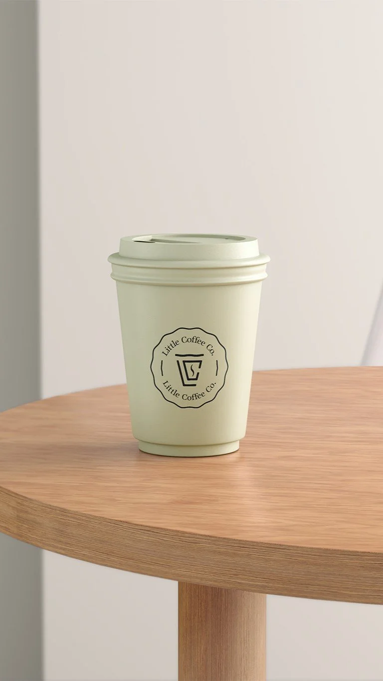 To-go coffee cup from Little Coffee Co, a coffee cart catering service in Madison, WI, placed on a wooden table