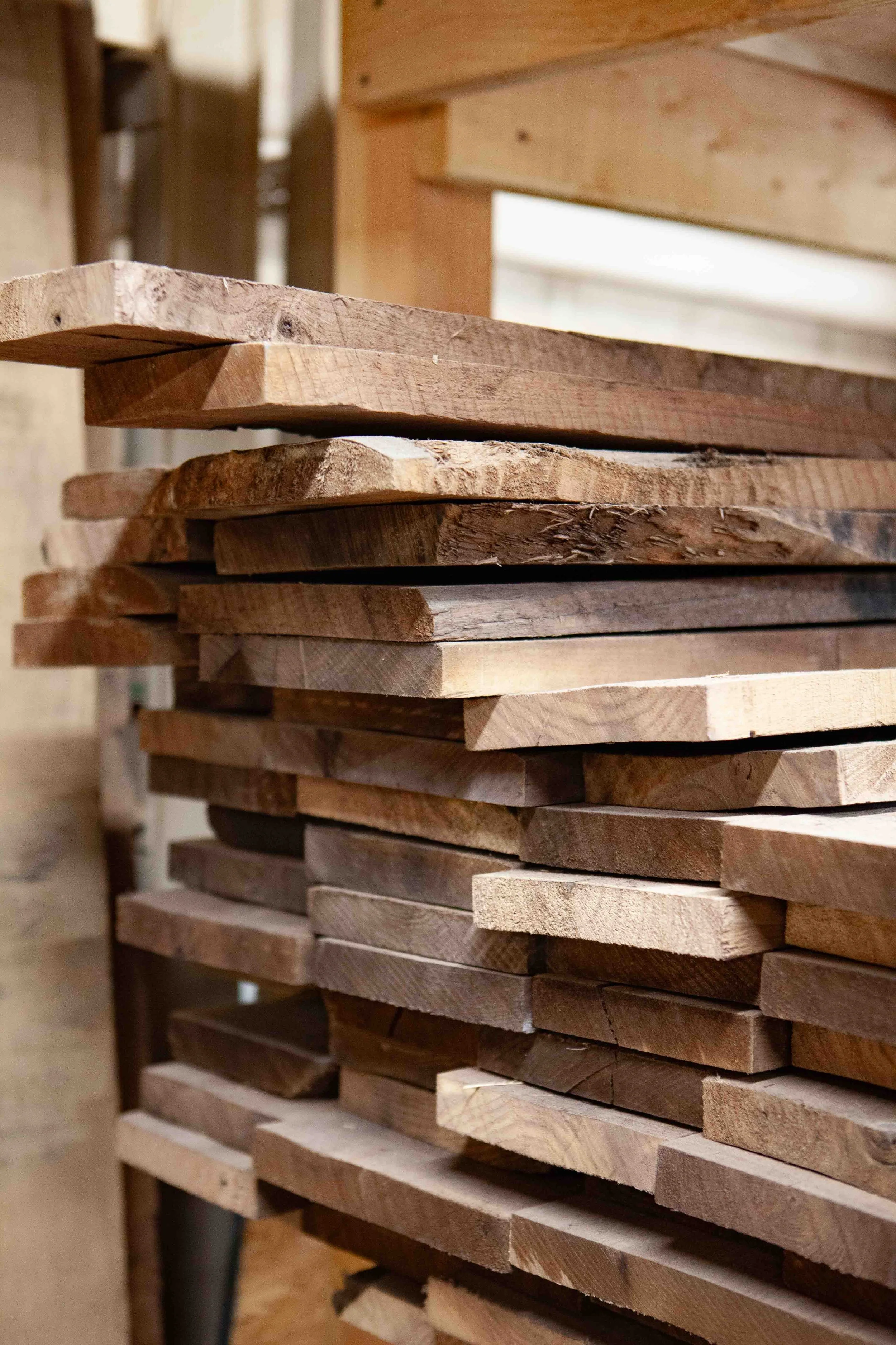 Stacked wooden planks arranged in a workshop or carpentry shop.