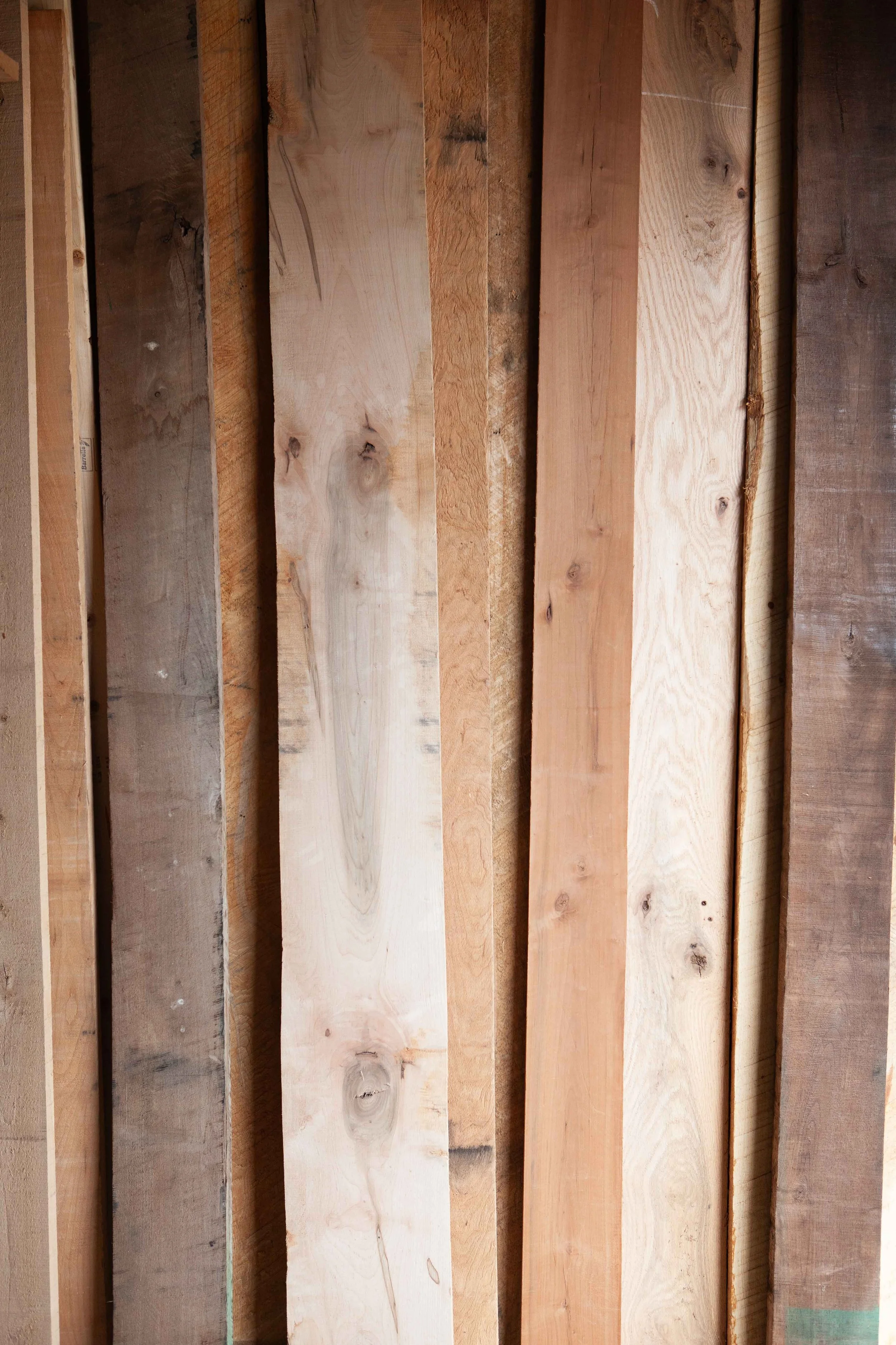 Multiple wooden planks in various shades and grains, stacked vertically.