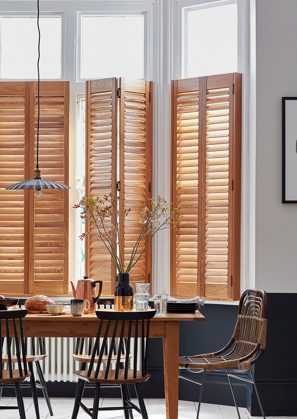 Natural wood café style window shutters with open louvres fitted to tall dining room windows.