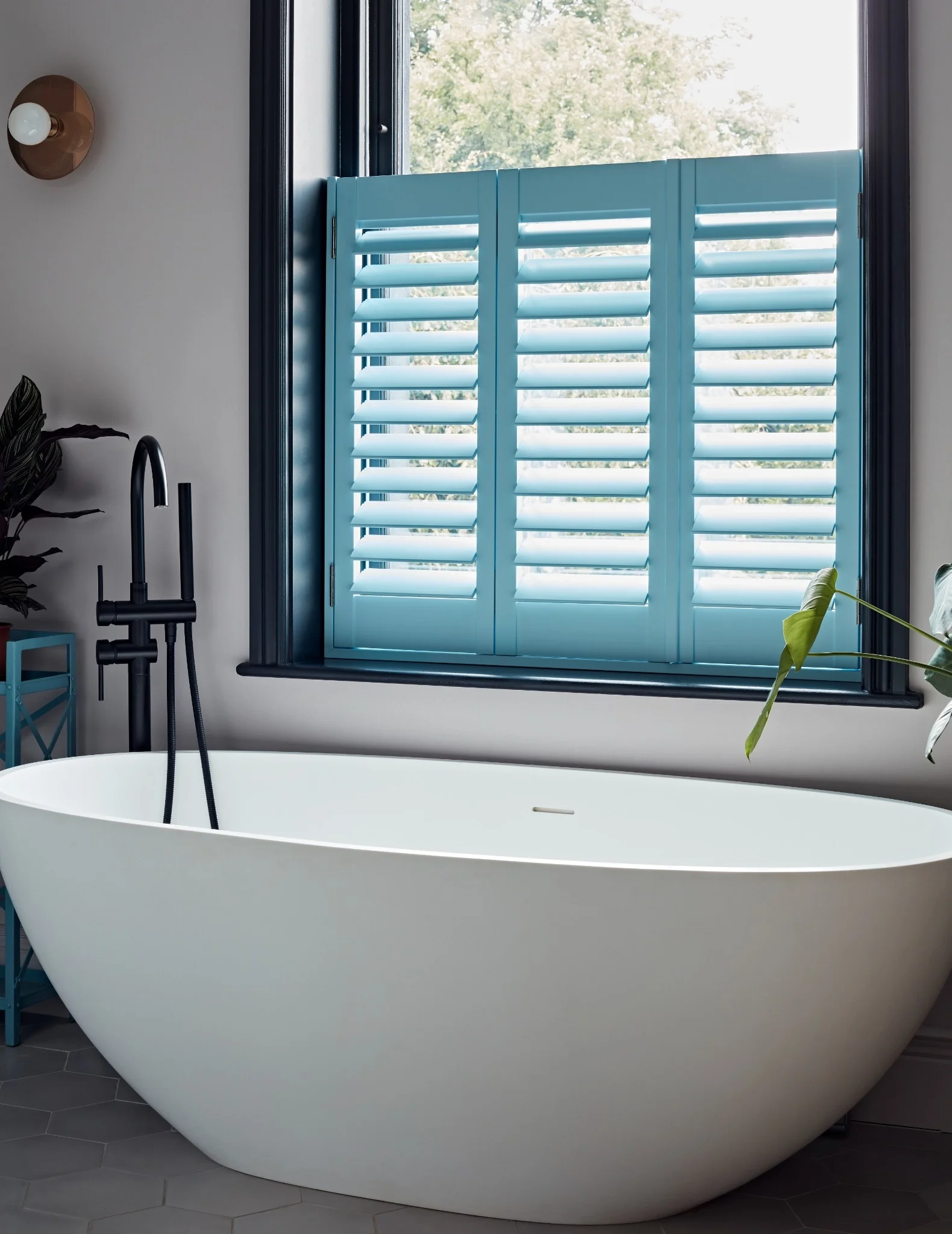 Patoma custom blue Hybrawood café style plantation shutters in a modern bathroom, providing bespoke privacy, adjustable daylight and a durable low-maintenance finish.