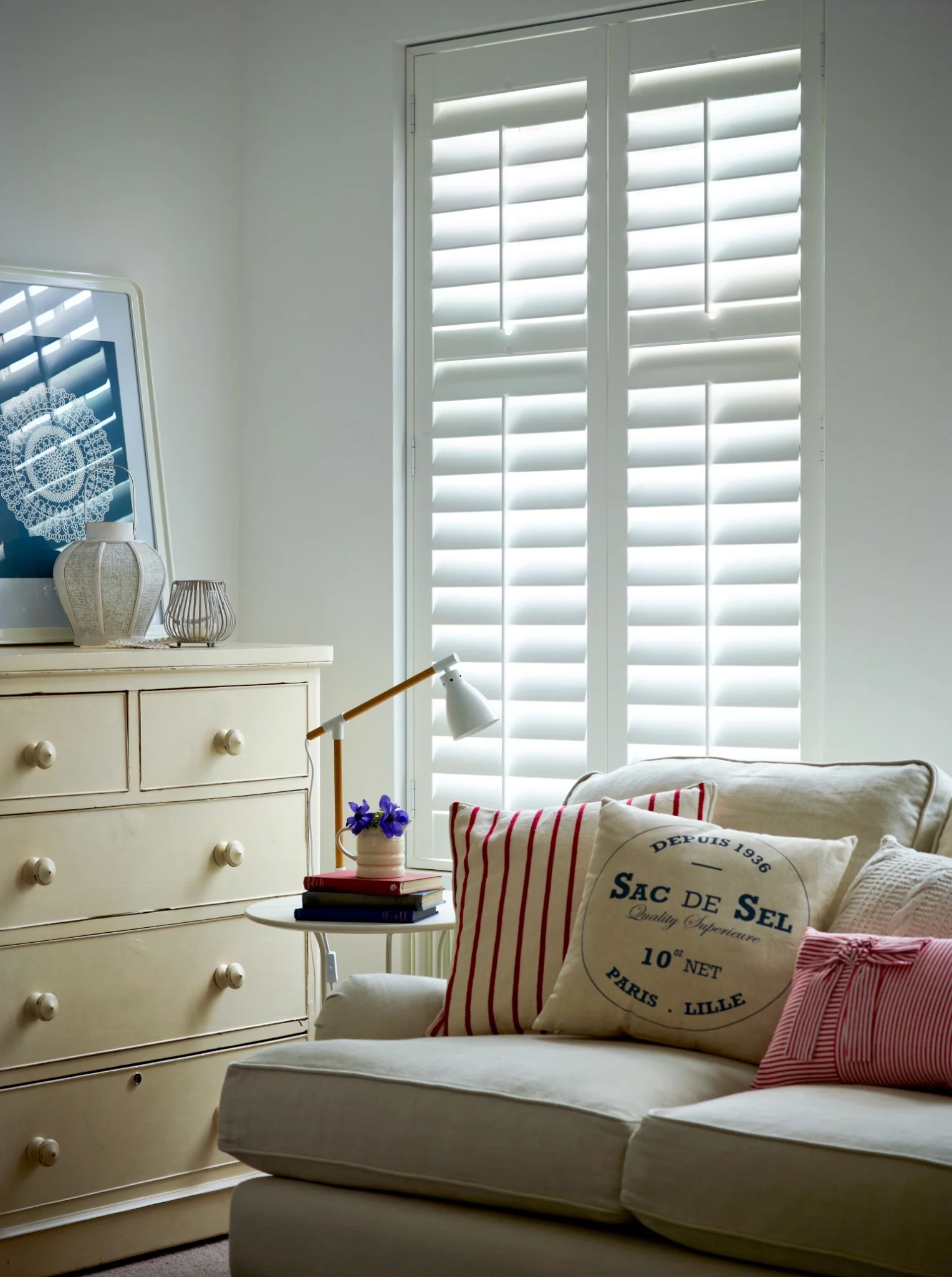 Patoma white Basswood full height plantation shutters with a mid rail installed in a bright living room, offering bespoke privacy, light control and timeless interior styling.