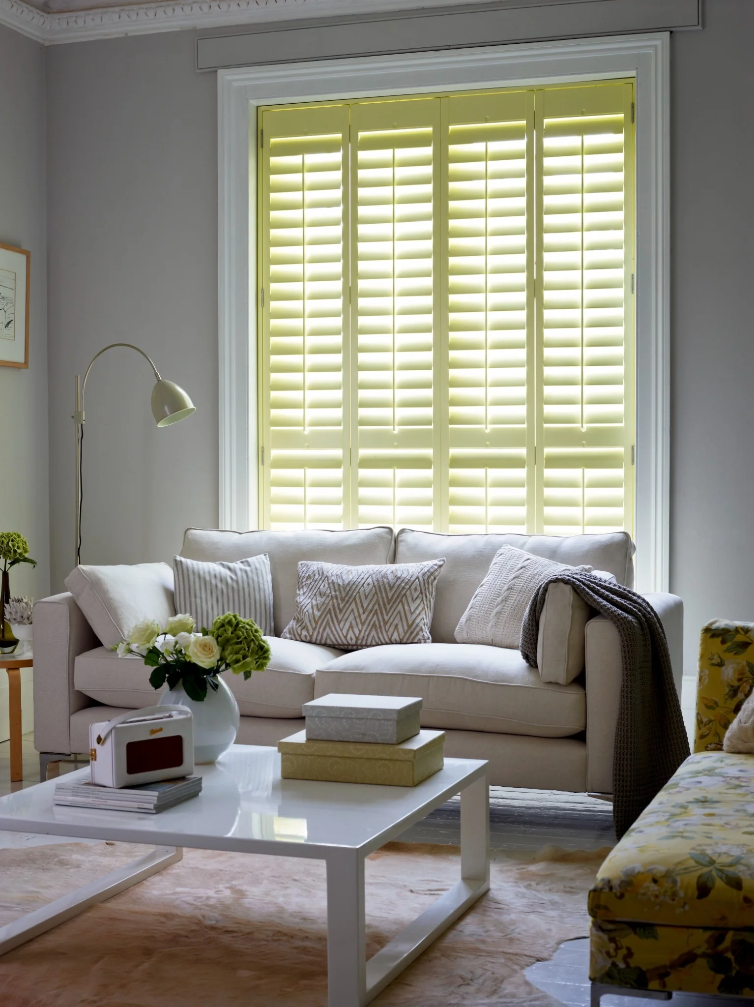 Patoma custom yellow Paulownia full height plantation shutters with closed louvres in a contemporary lounge, providing complete privacy, elegant styling and bespoke made-to-measure craftsmanship.