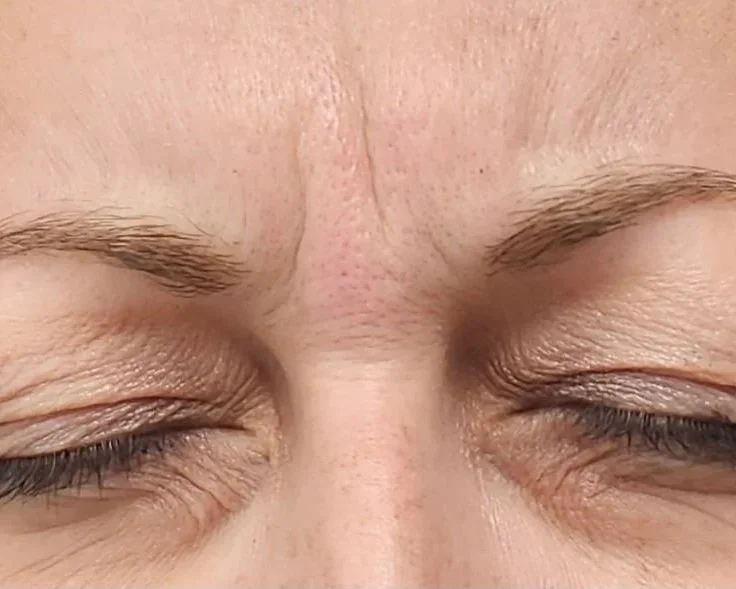 Close-up of a person's face with eyes closed, showing their eyebrows, eyelids, and skin texture.