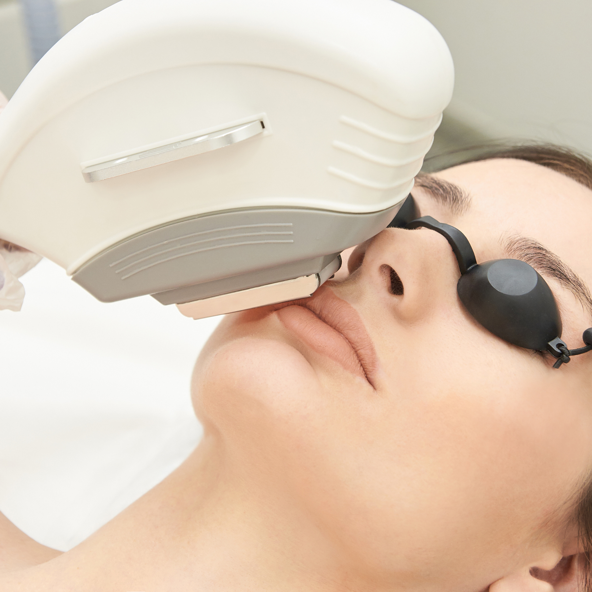 Close-up of a person's face lying on a pillow with a medical device placed on their forehead.