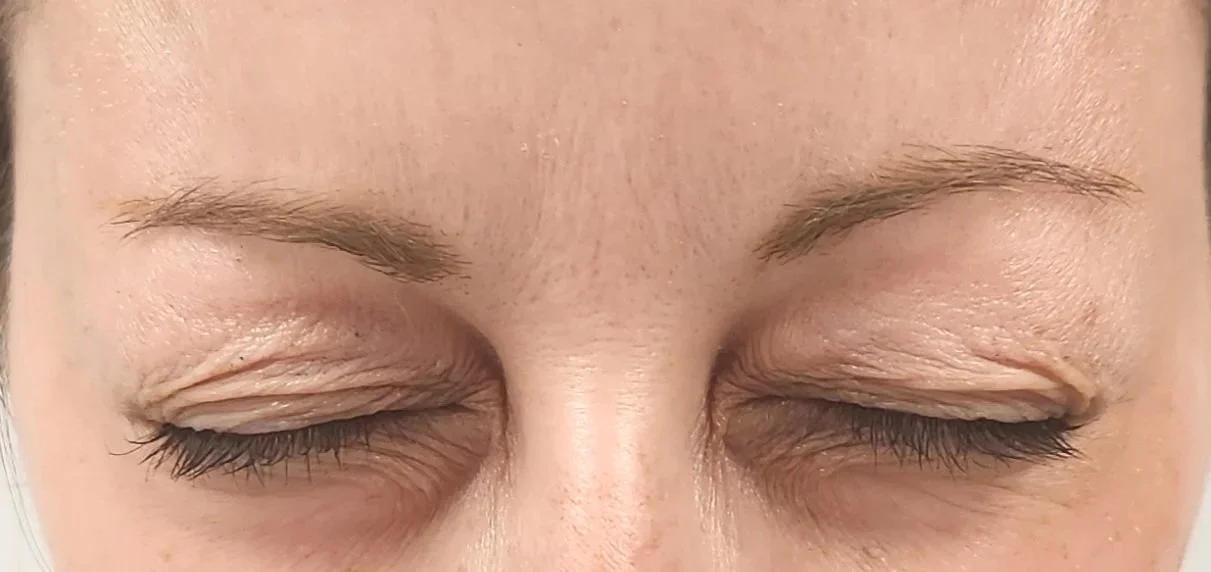 Close-up of a person's face with their eyes closed, showing their eyebrows and eyelashes.