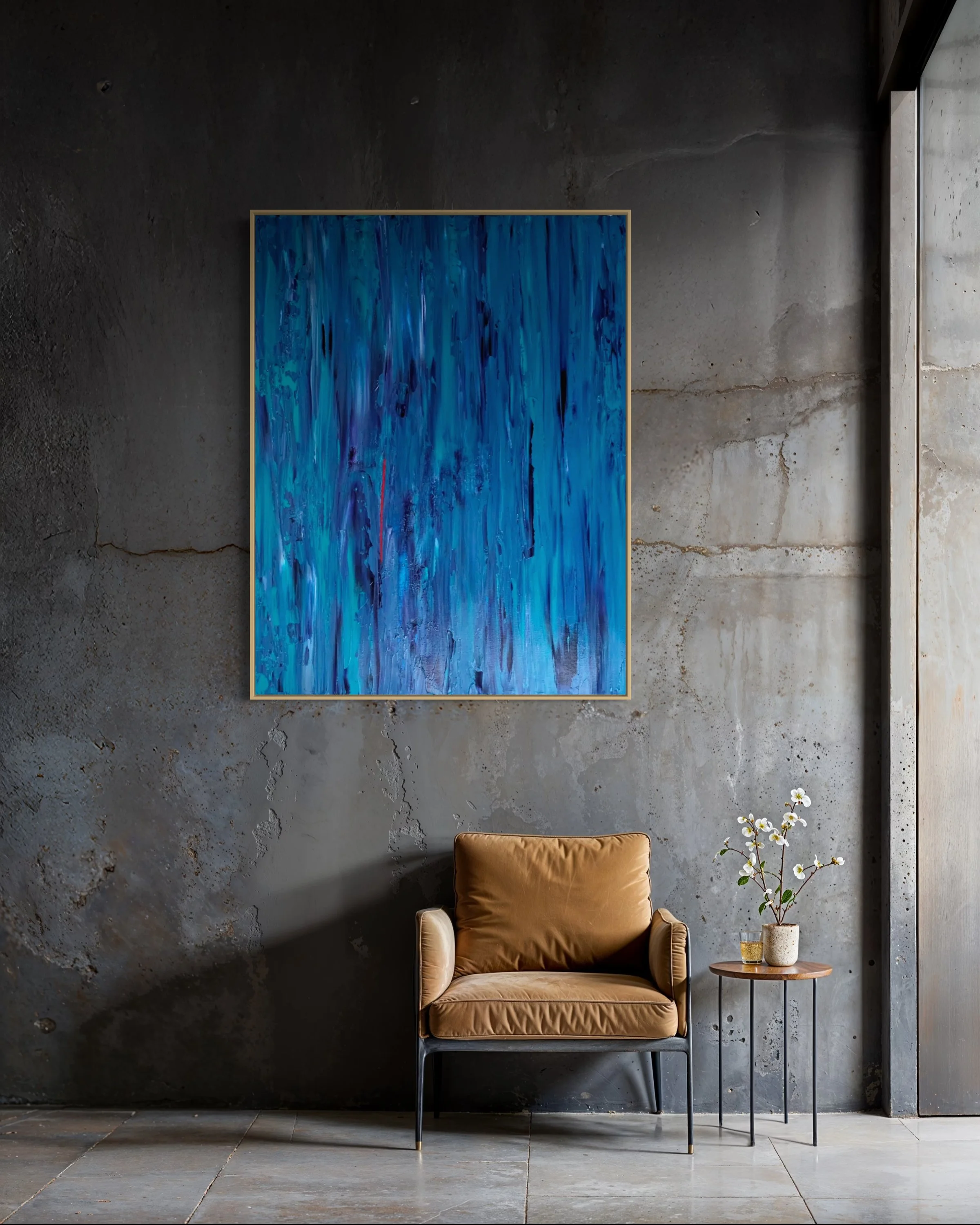 Interior space with a dark grey concrete wall, a yellowish-brown armchair, a small round wooden side table with potted white flowers, and a blue abstract painting, HEARTBEAT by Paul Bell on the wall.