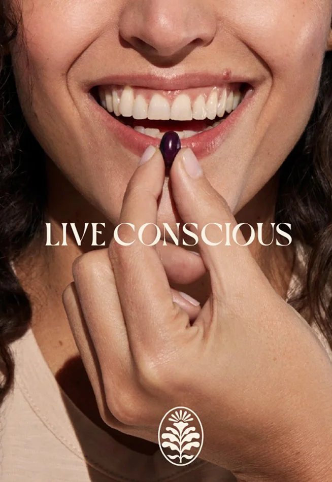 Close-up of a woman smiling and holding a purple pill between her thumb and index finger with text 'Live Conscious' and a logo beneath.