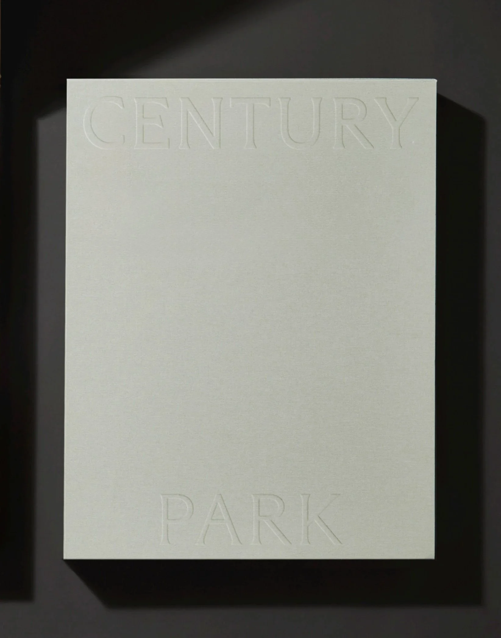 A white card with embossed text reading "CENTURY" at the top and partially visible embossed text reading "PARK" at the bottom, placed on a black surface.