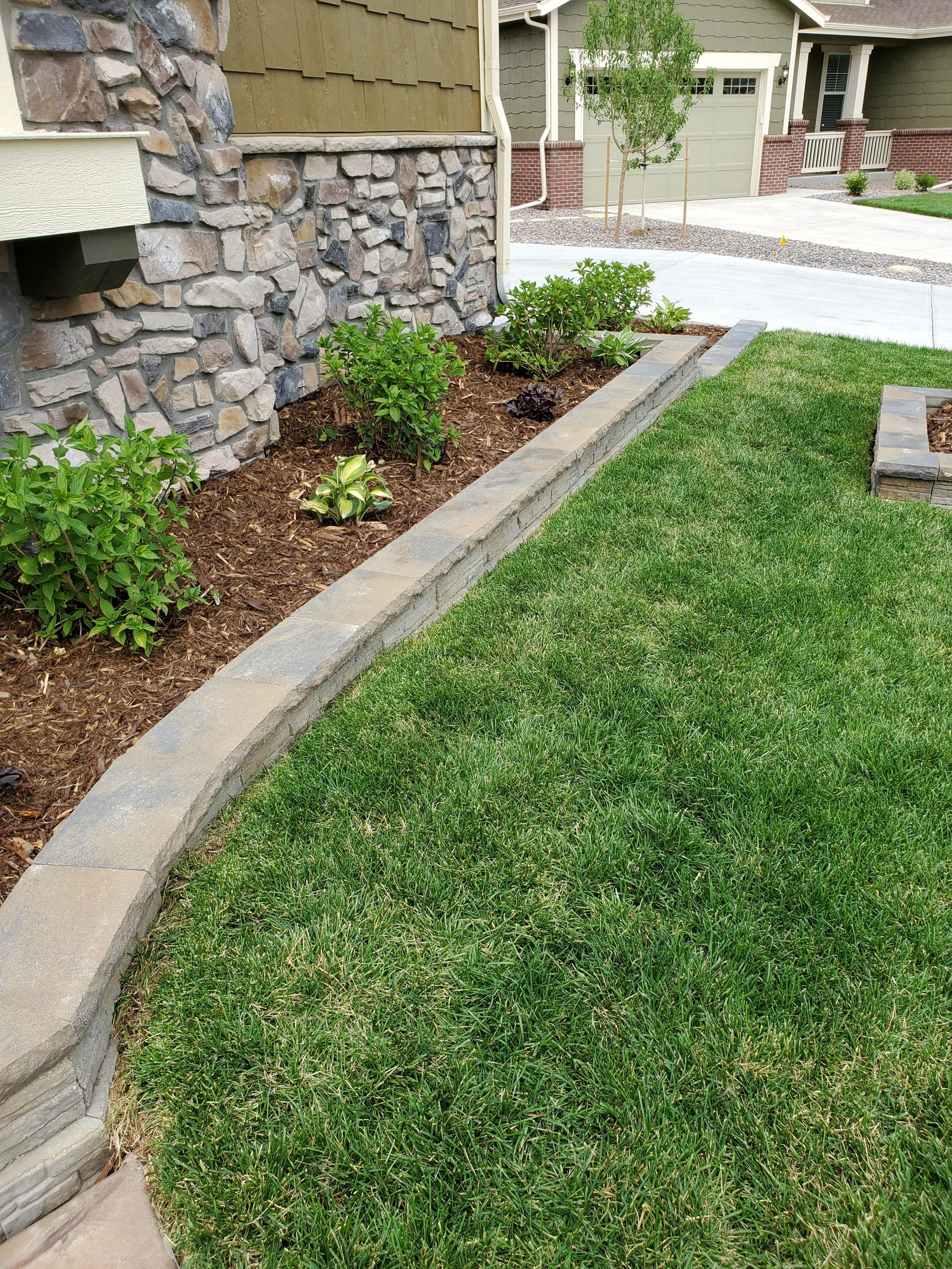 Parker front yard retaining wall planter with small shrubs and mulch