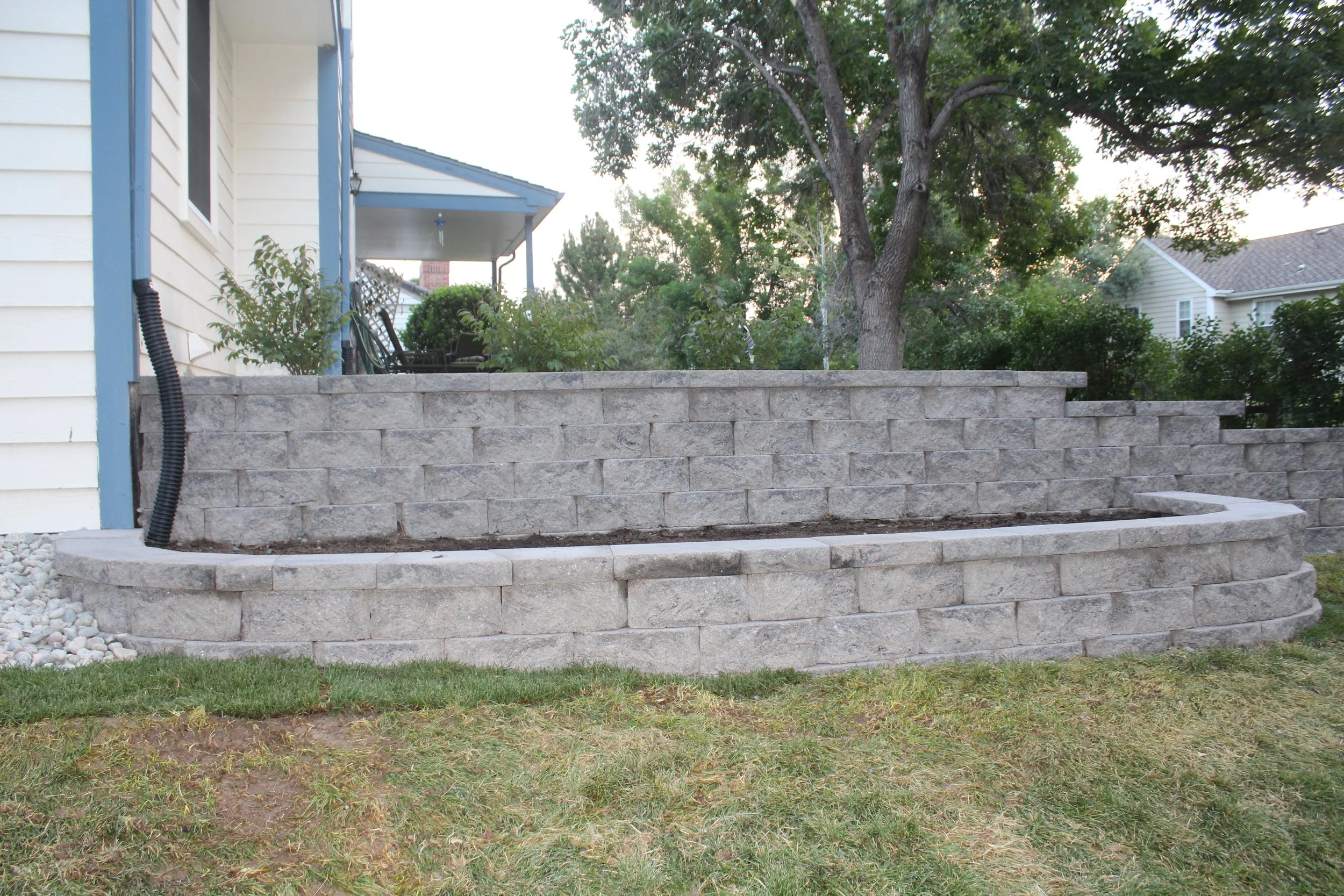 Retaining wall block and cap planter off side of retaining wall along elevated back yard