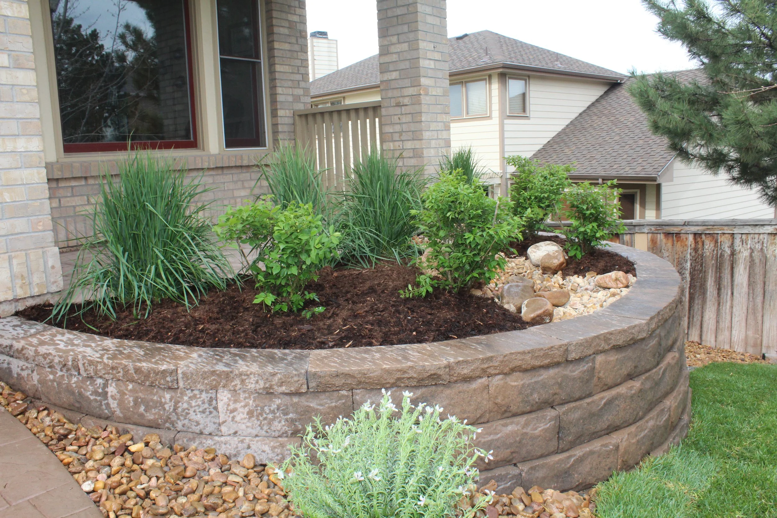 Retaining wall planter with shrubs and dry river