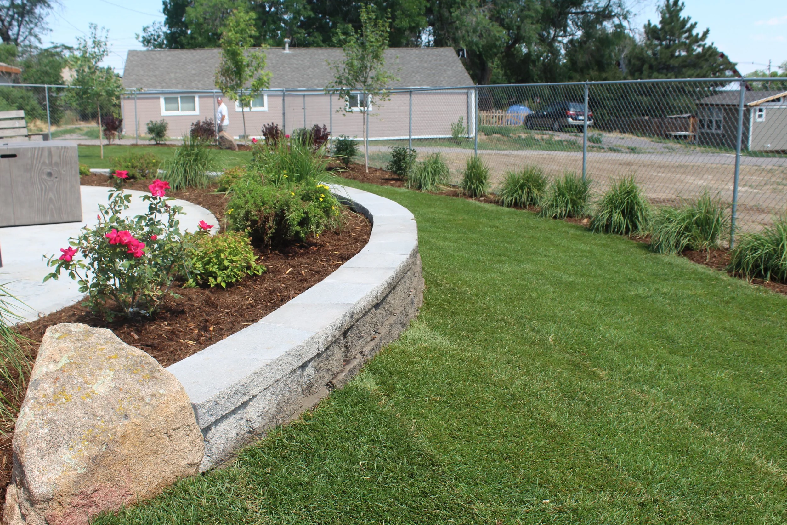 Retaining wall block and cap planter with boulders and roses