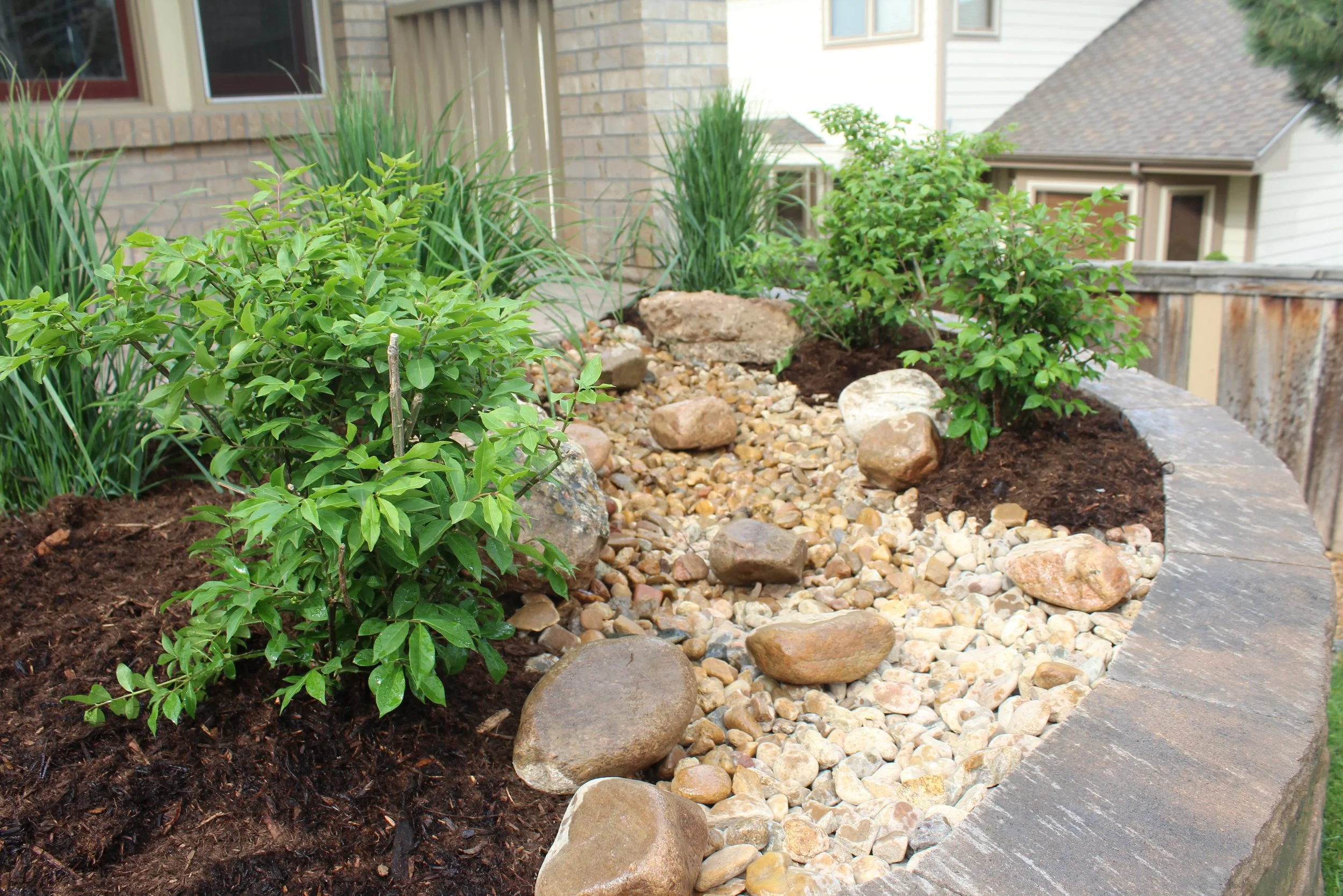 Retaining wall block and cap planter with dry river and shrubs