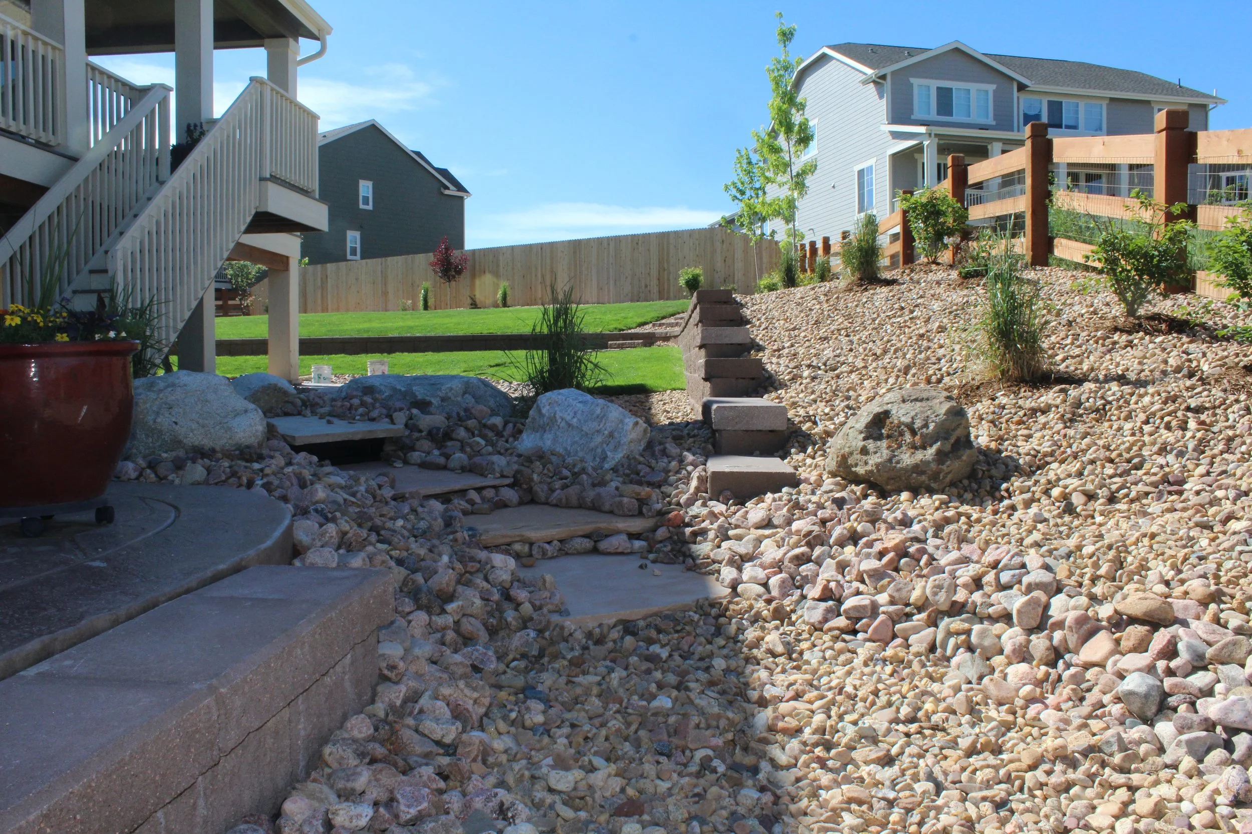 Pondless water feature with flagstones river rock and cobble surrounded by fountain grasses