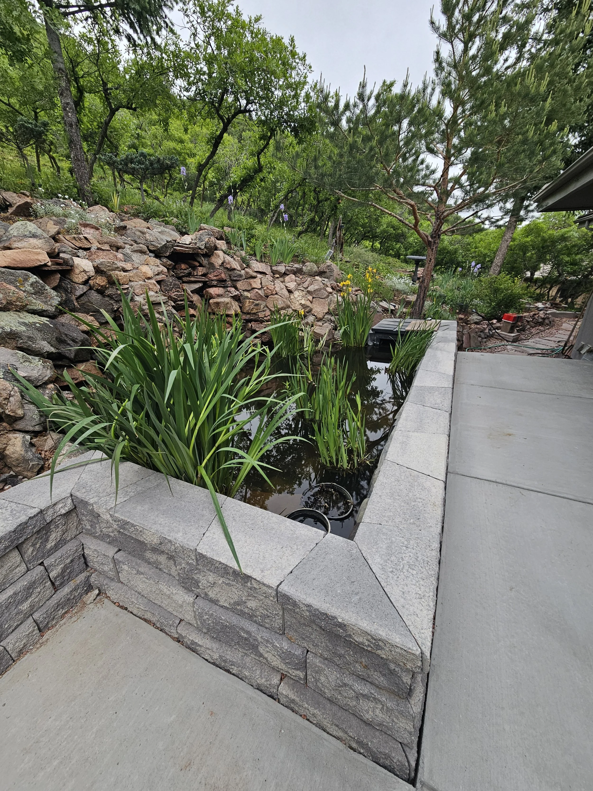 Retaining wall block and cap holding Koi pond in place on the side of the slope 